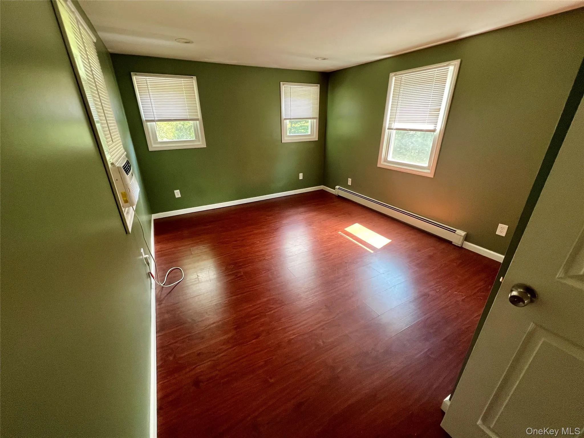 Spacious bedroom with multiple windows providing plenty of natural light and hardwood-style flooring. Spacious bedroom with multiple windows providing plenty of natural light and hardwood-style flooring.