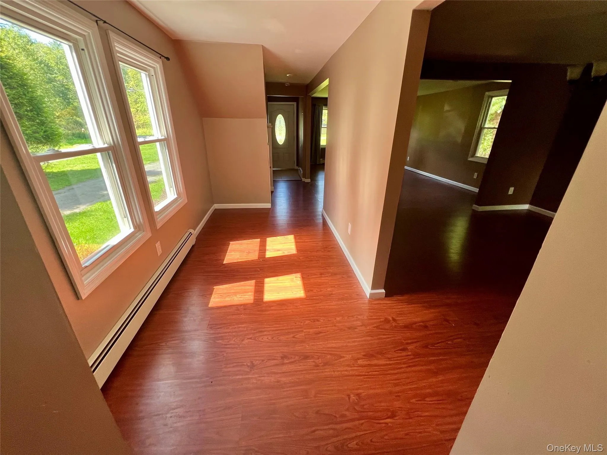 Wood-finish flooring throughout, bright white window trim, and a white front entry door with an oval glass insert Wood-finish flooring throughout, bright white window trim, and a white front entry door with an oval glass insert