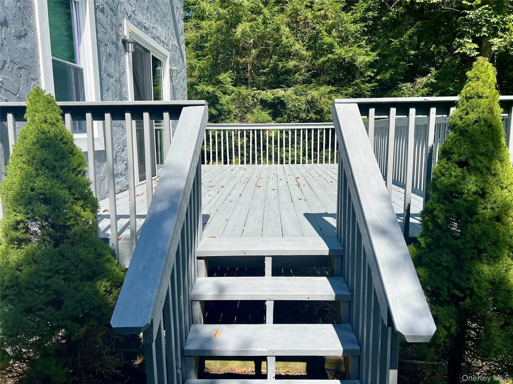 Multi-level wood deck with a gray finish, featuring stairs and a railing system Multi-level wood deck with a gray finish, featuring stairs and a railing system