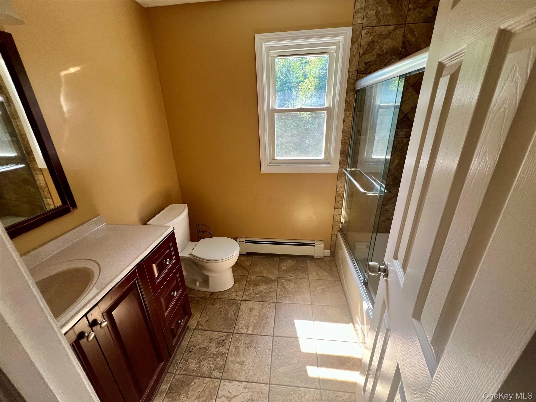 Bathroom with a dark wood-finish vanity, integrated sink, and a framed mirror Bathroom with a dark wood-finish vanity, integrated sink, and a framed mirror