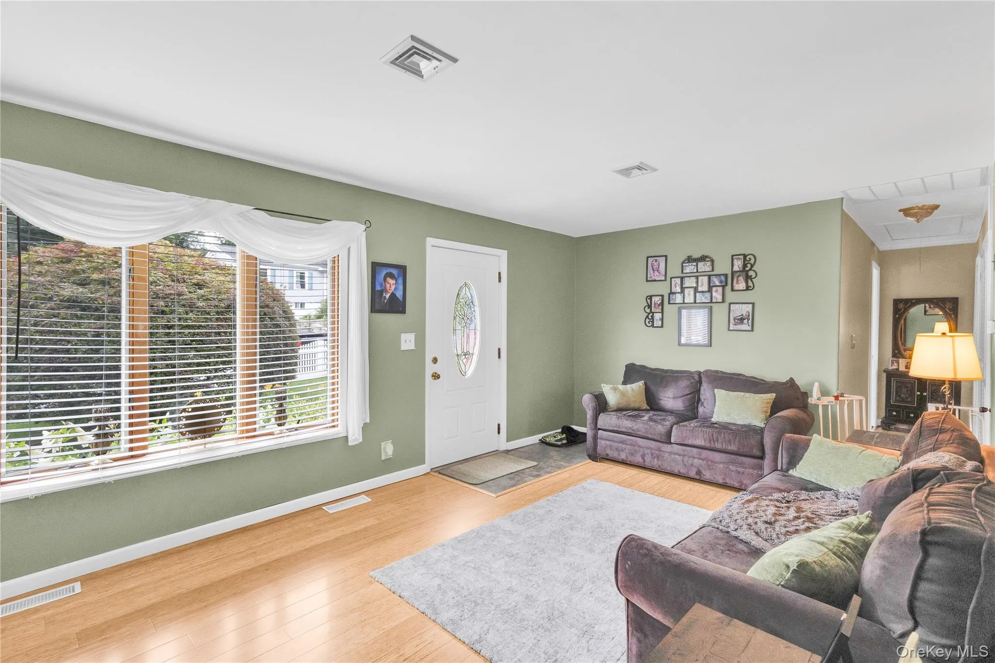 Wood-finish flooring, large multi-pane window, white entry door with decorative glass insert, and recessed ceiling light fixtures Wood-finish flooring, large multi-pane window, white entry door with decorative glass insert, and recessed ceiling light fixtures