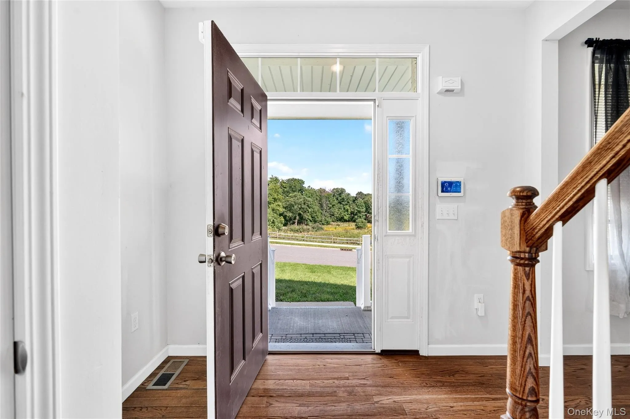 Rich wood-finish flooring, a paneled front door, and a decorative transom window above the entryway Rich wood-finish flooring, a paneled front door, and a decorative transom window above the entryway