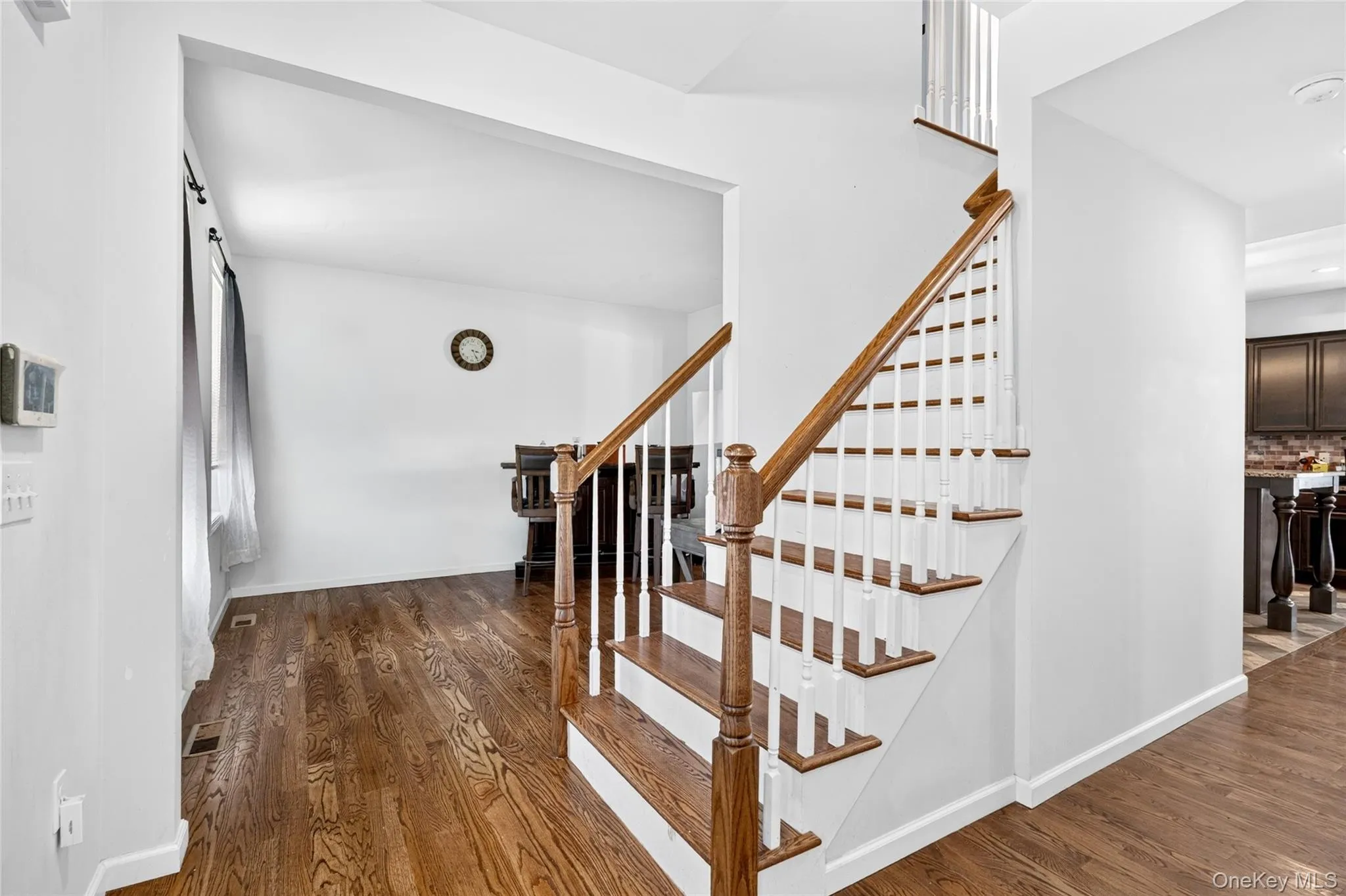 Hardwood flooring, white walls, wood-finish staircase with white risers, and wood-finish handrails Hardwood flooring, white walls, wood-finish staircase with white risers, and wood-finish handrails