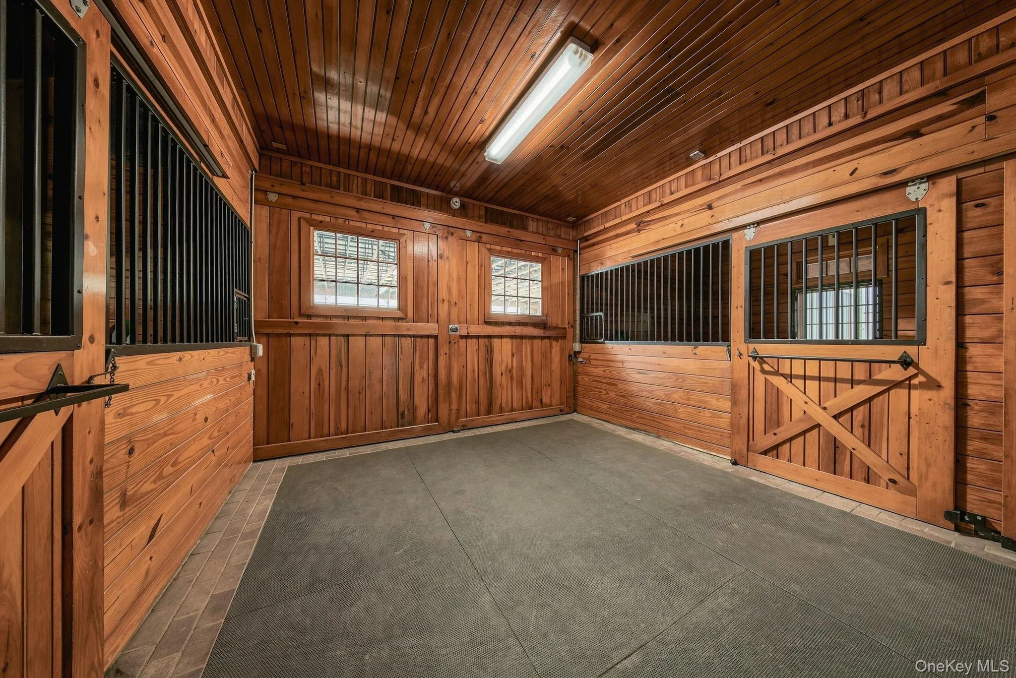 View of the main barn aisle and doors to the indoor arena. View of the main barn aisle and doors to the indoor arena.