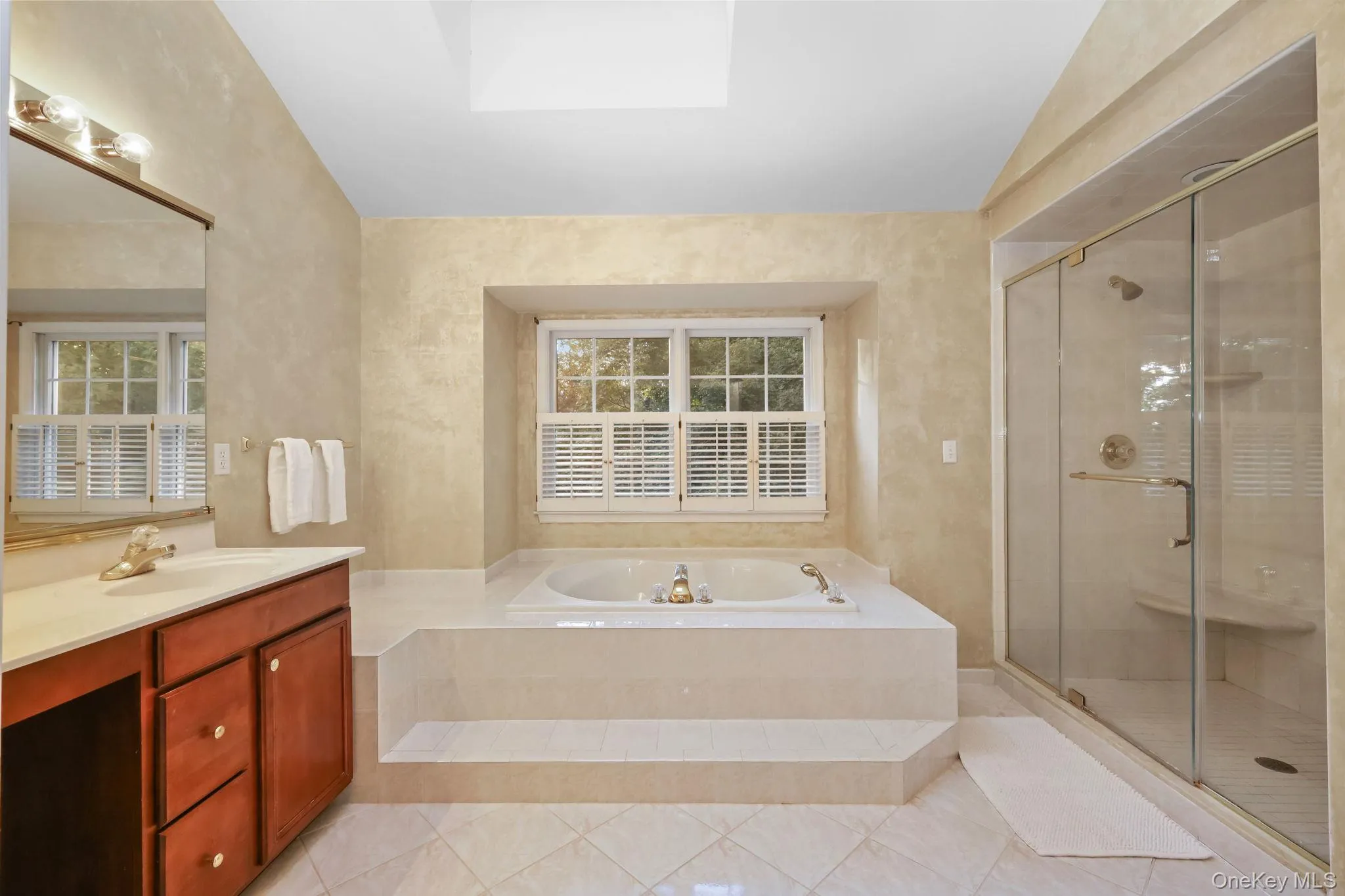 The marble primary bathroom features an oversized double vanity, whirlpool tub, large glass-enclosed walk-in shower and a linen closet. The marble primary bathroom features an oversized double vanity, whirlpool tub, large glass-enclosed walk-in shower and a linen closet.