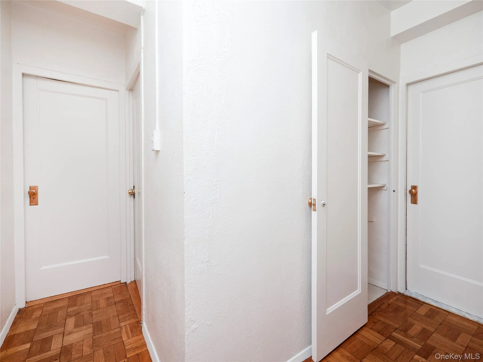 Hallway with wood-finish parquet flooring, white painted walls Hallway with wood-finish parquet flooring, white painted walls