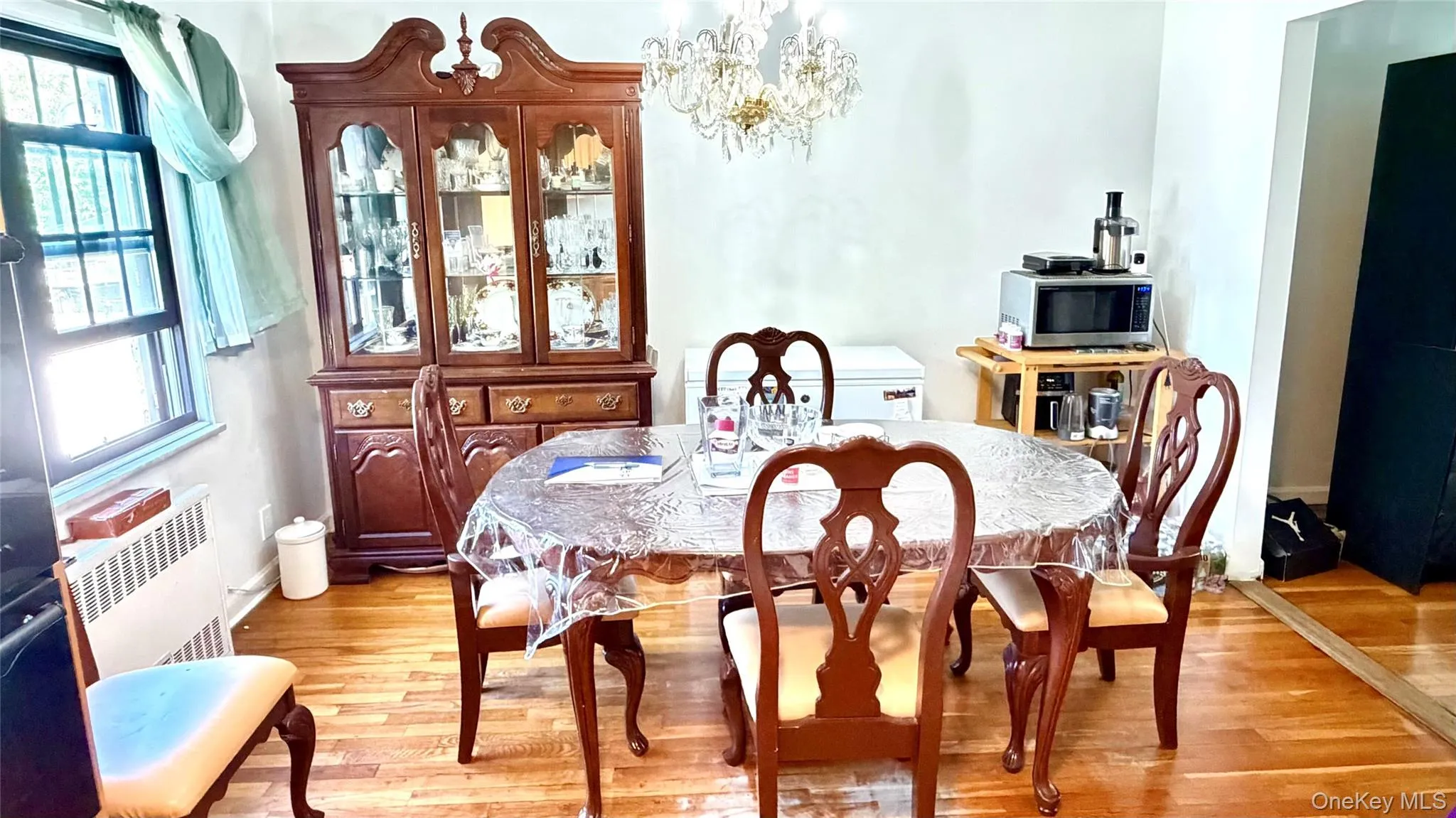 Hardwood flooring, window with grilles, built-in display cabinet, and overhead chandelier Hardwood flooring, window with grilles, built-in display cabinet, and overhead chandelier