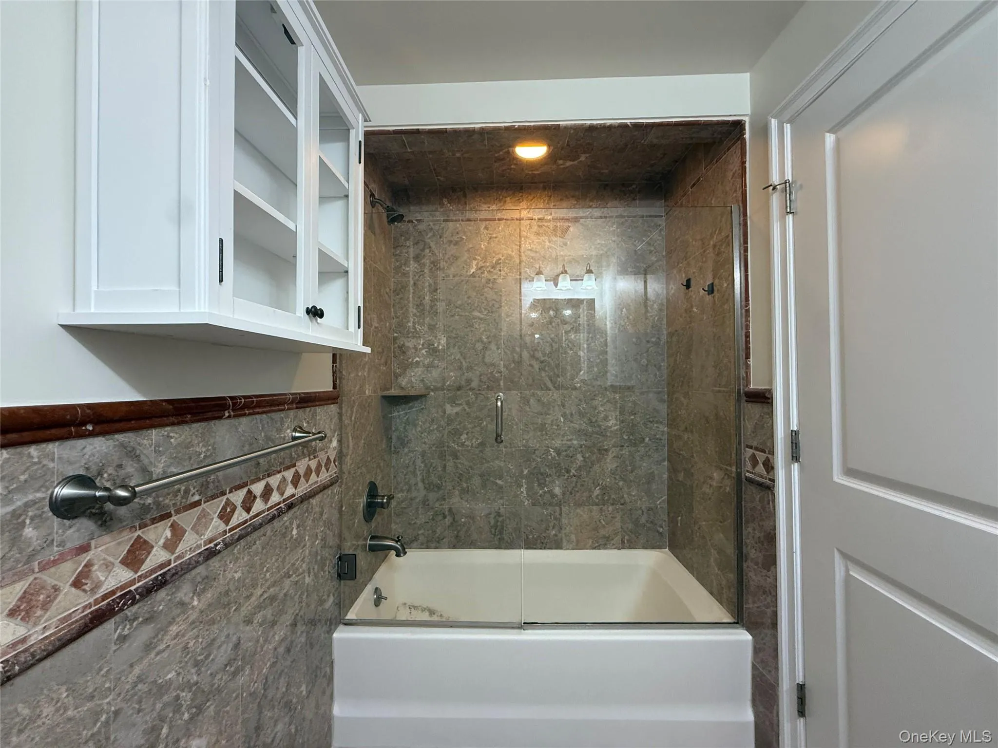Updated bathroom with stone and tile finishes and glass door on tub/shower Updated bathroom with stone and tile finishes and glass door on tub/shower