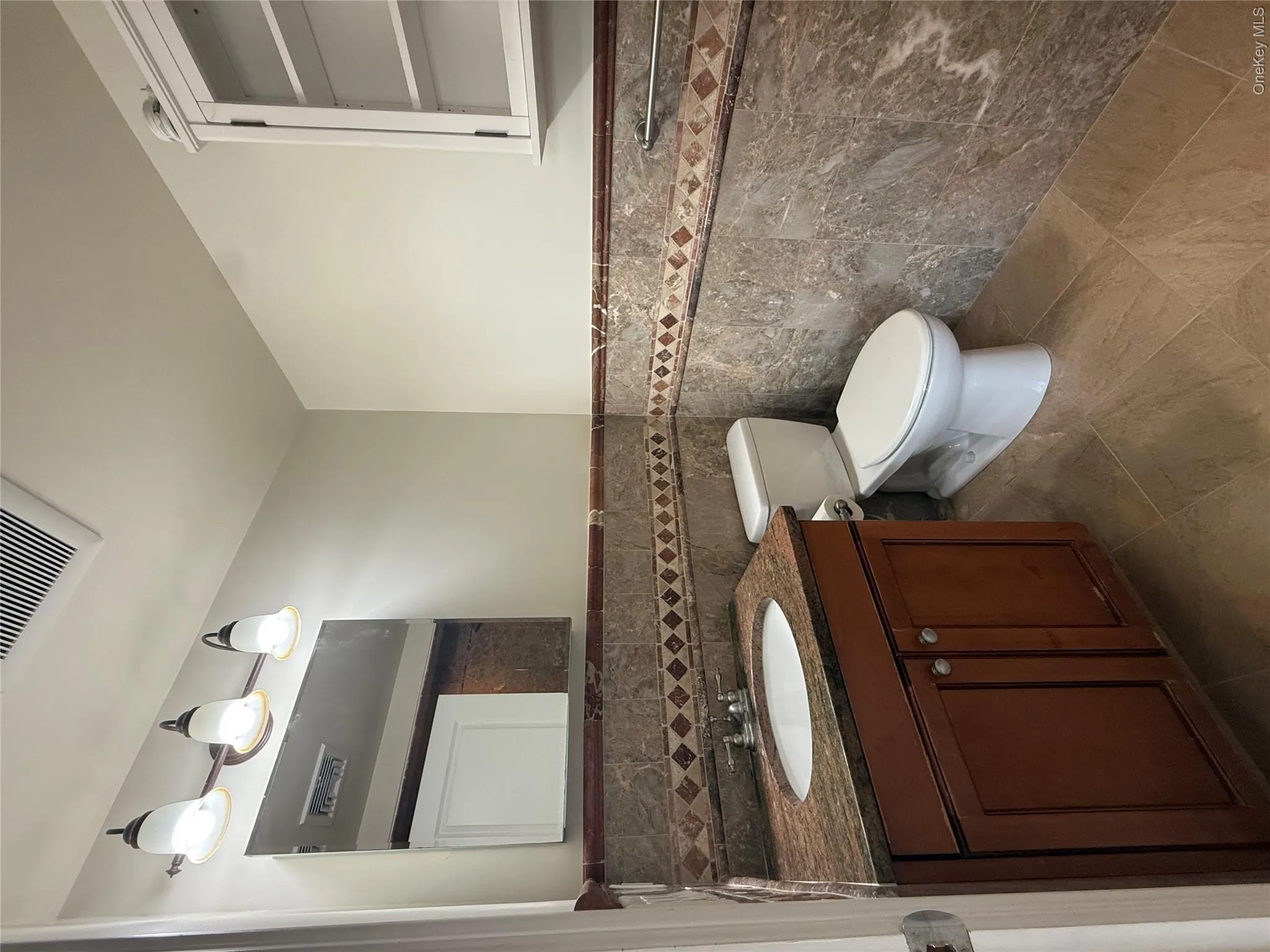 Updated bathroom with stone and tile finishes and glass door on tub/shower Updated bathroom with stone and tile finishes and glass door on tub/shower