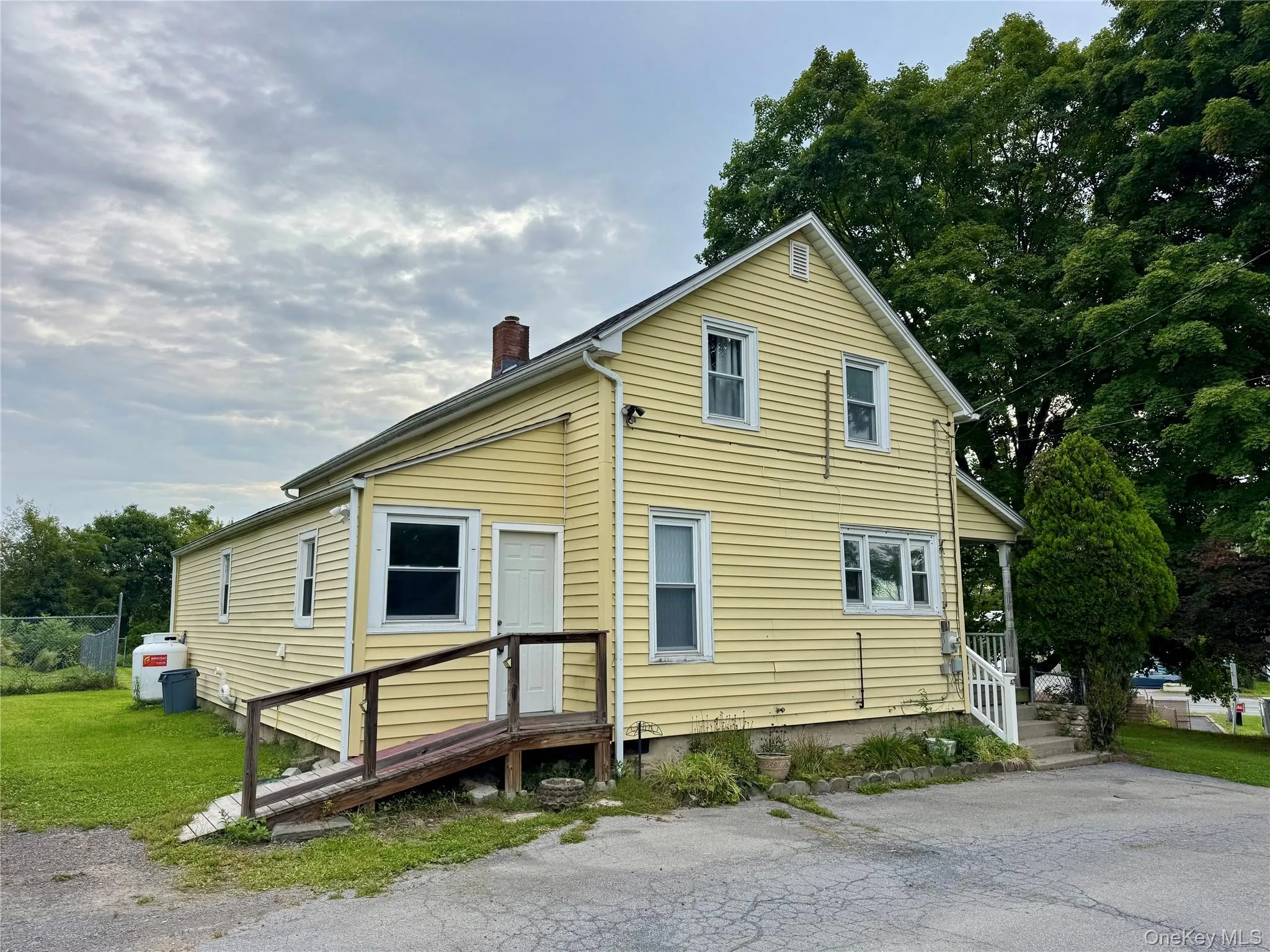 Exterior view of the home featuring a side entrance with ramp access and off-street parking. Exterior view of the home featuring a side entrance with ramp access and off-street parking.
