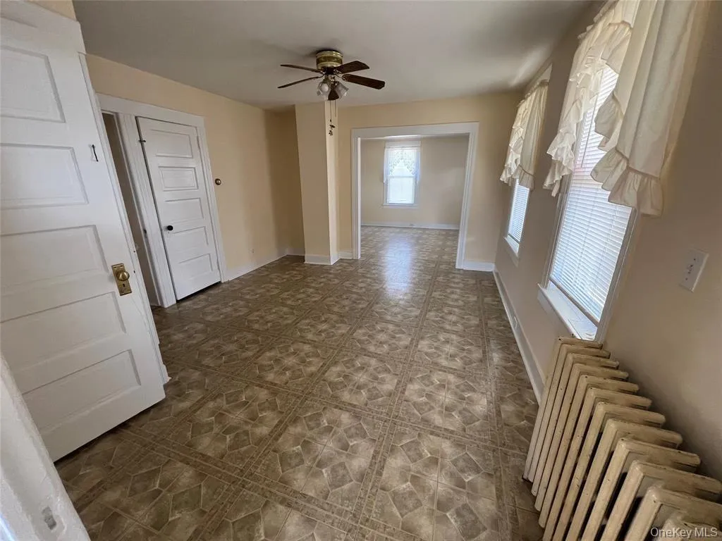 Spacious interior room with multiple windows, ceiling fan, and an open layout leading into an additional living area. Spacious interior room with multiple windows, ceiling fan, and an open layout leading into an additional living area.