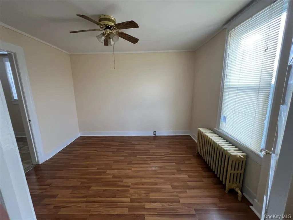 Bedroom featuring crown molding, dark hardwood / wood-style floors, radiator heating unit, and ceiling fan Bedroom featuring crown molding, dark hardwood / wood-style floors, radiator heating unit, and ceiling fan