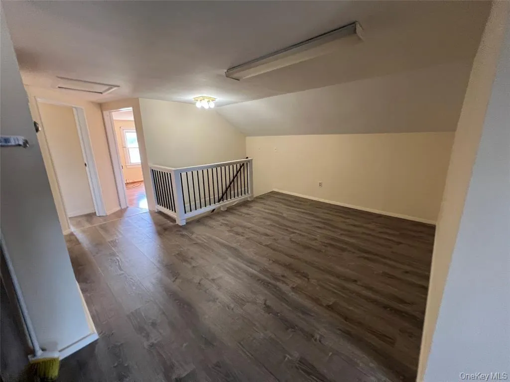 Wood-finish flooring throughout, a white painted railing with black spindles, and neutral wall tones Wood-finish flooring throughout, a white painted railing with black spindles, and neutral wall tones