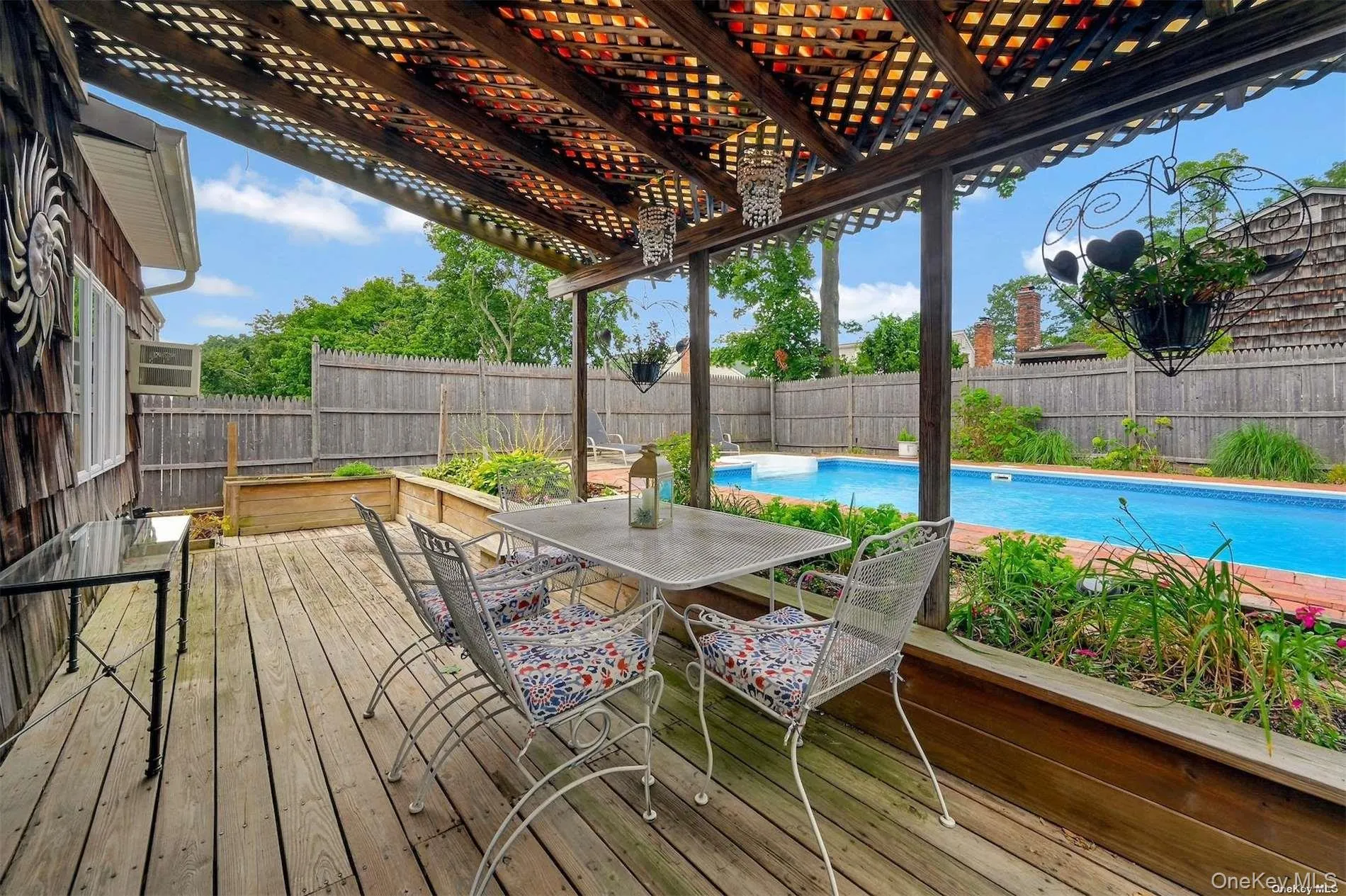 Expansive wooden deck with a slatted pergola, overlooking an in-ground swimming pool Expansive wooden deck with a slatted pergola, overlooking an in-ground swimming pool