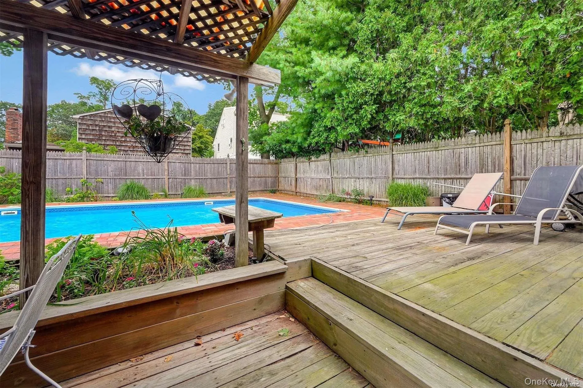 Expansive backyard featuring a large swimming pool, wood deck, and wood lattice pergola Expansive backyard featuring a large swimming pool, wood deck, and wood lattice pergola