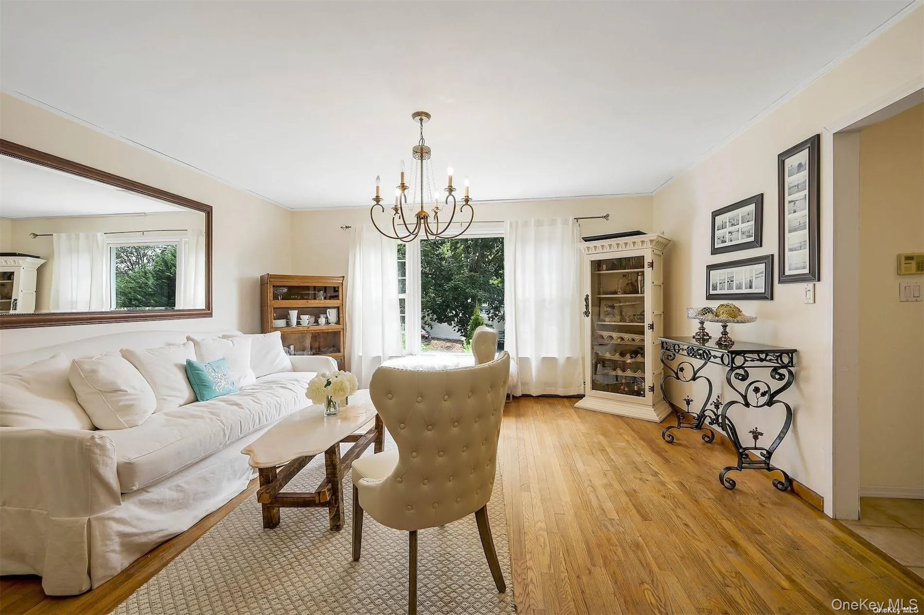 Hardwood flooring throughout, with a classic chandelier light fixture, recessed wall niche, and natural light from exterior windows Hardwood flooring throughout, with a classic chandelier light fixture, recessed wall niche, and natural light from exterior windows