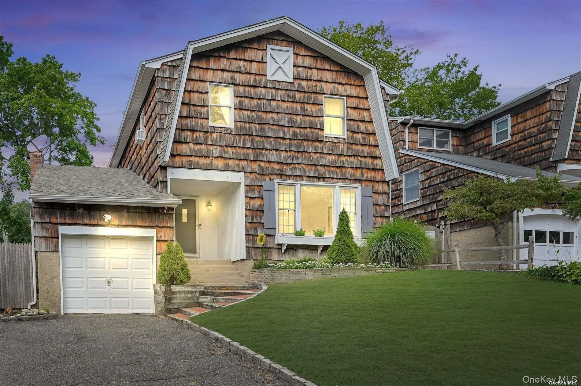 Gambrel roofline with cedar shake siding, featuring a covered entry, attached garage, and landscaped front yard Gambrel roofline with cedar shake siding, featuring a covered entry, attached garage, and landscaped front yard