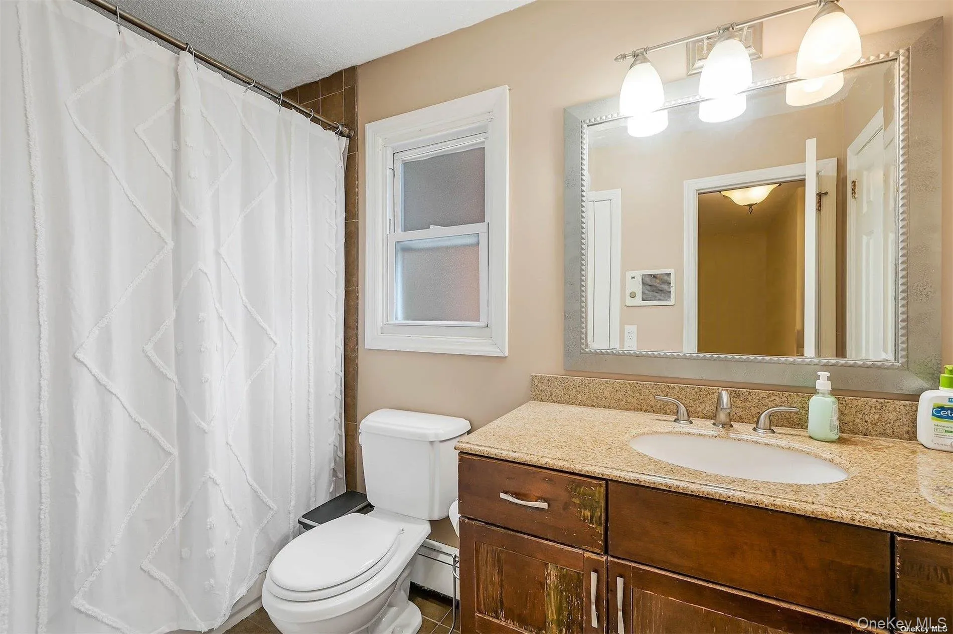 Bathroom featuring a vanity with a granite-style countertop, undermount sink, and dark wood-finish cabinetry Bathroom featuring a vanity with a granite-style countertop, undermount sink, and dark wood-finish cabinetry