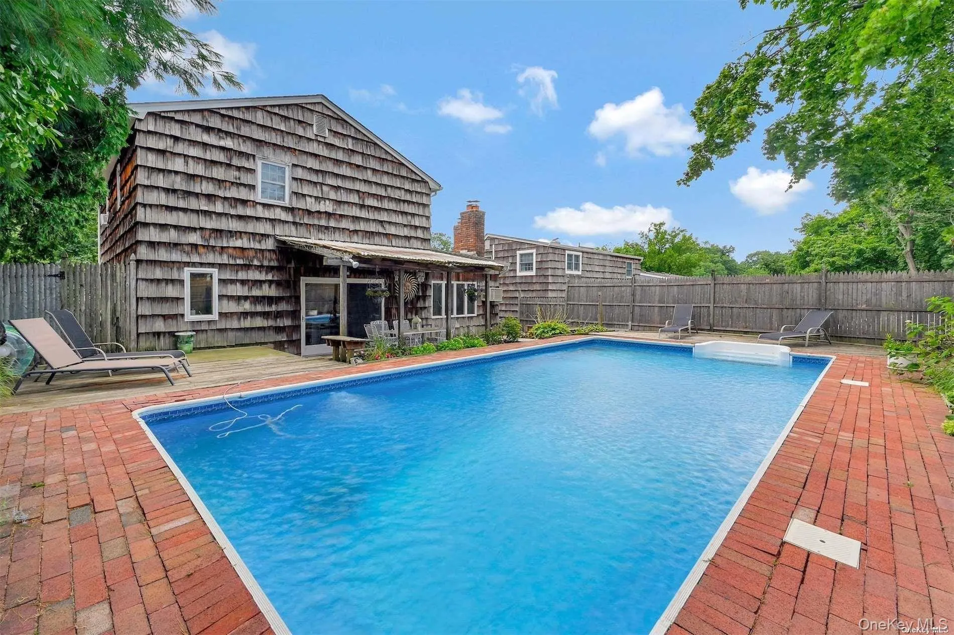 In-ground swimming pool with brick paver surround, wood-sided exterior, and covered patio In-ground swimming pool with brick paver surround, wood-sided exterior, and covered patio