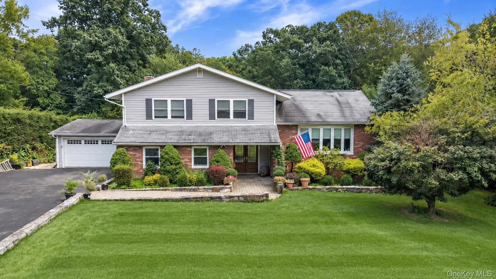 Exterior featuring a two-car garage, brick and siding facade, established landscaping, and a paver stone walkway Exterior featuring a two-car garage, brick and siding facade, established landscaping, and a paver stone walkway