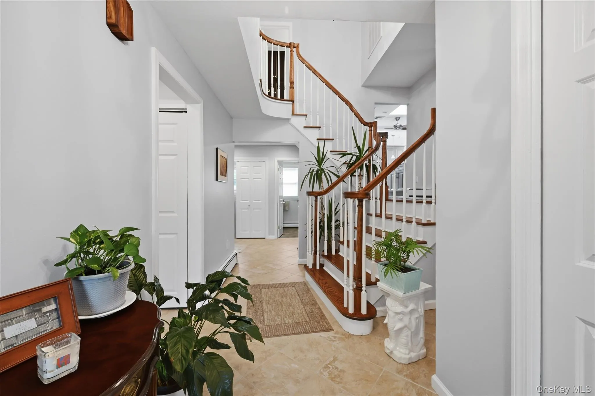Tiled flooring entry with a staircase featuring wood handrails and white balusters Tiled flooring entry with a staircase featuring wood handrails and white balusters