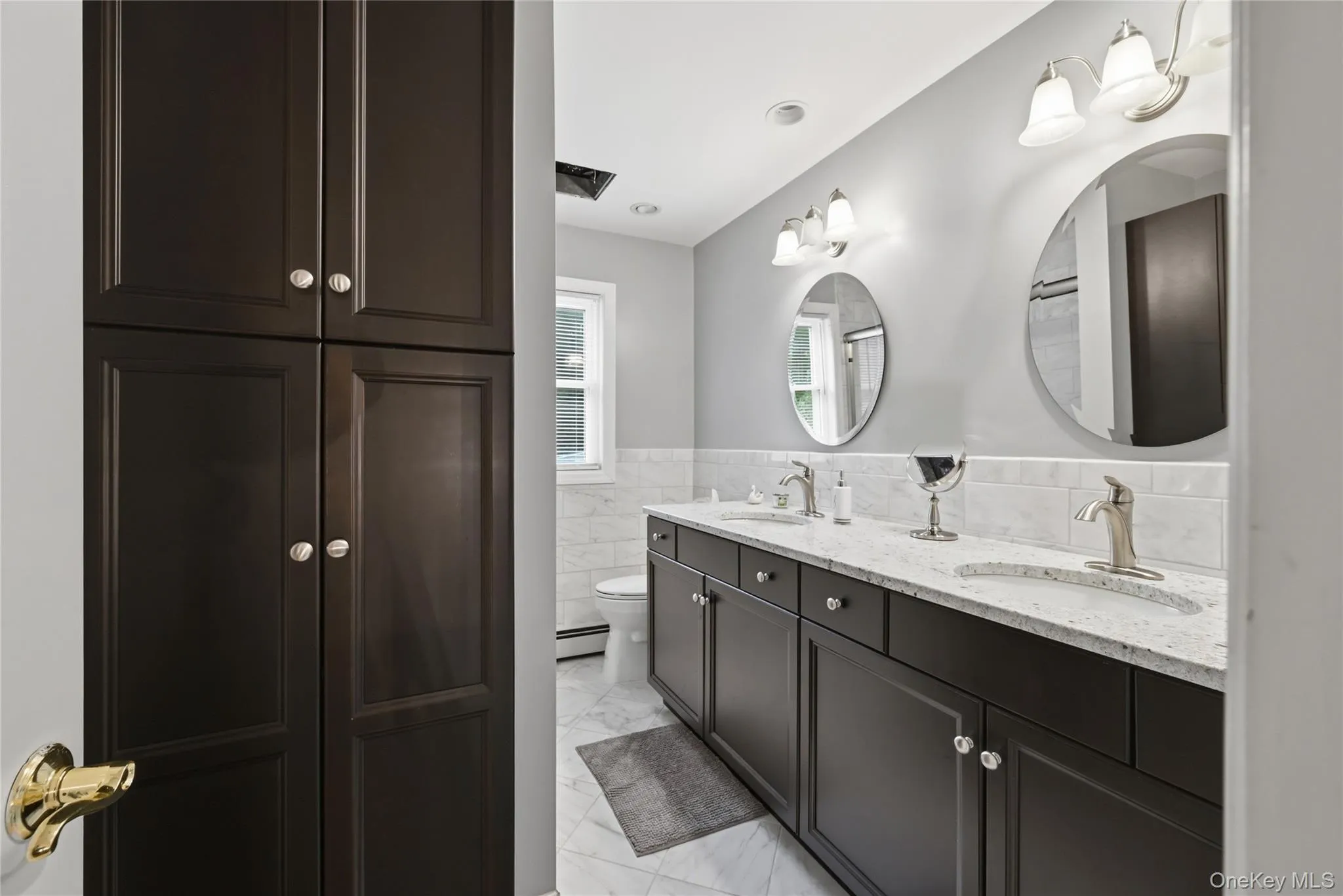 Double vanity with dark wood-finish cabinetry, light speckled countertops, and undermount sinks Double vanity with dark wood-finish cabinetry, light speckled countertops, and undermount sinks