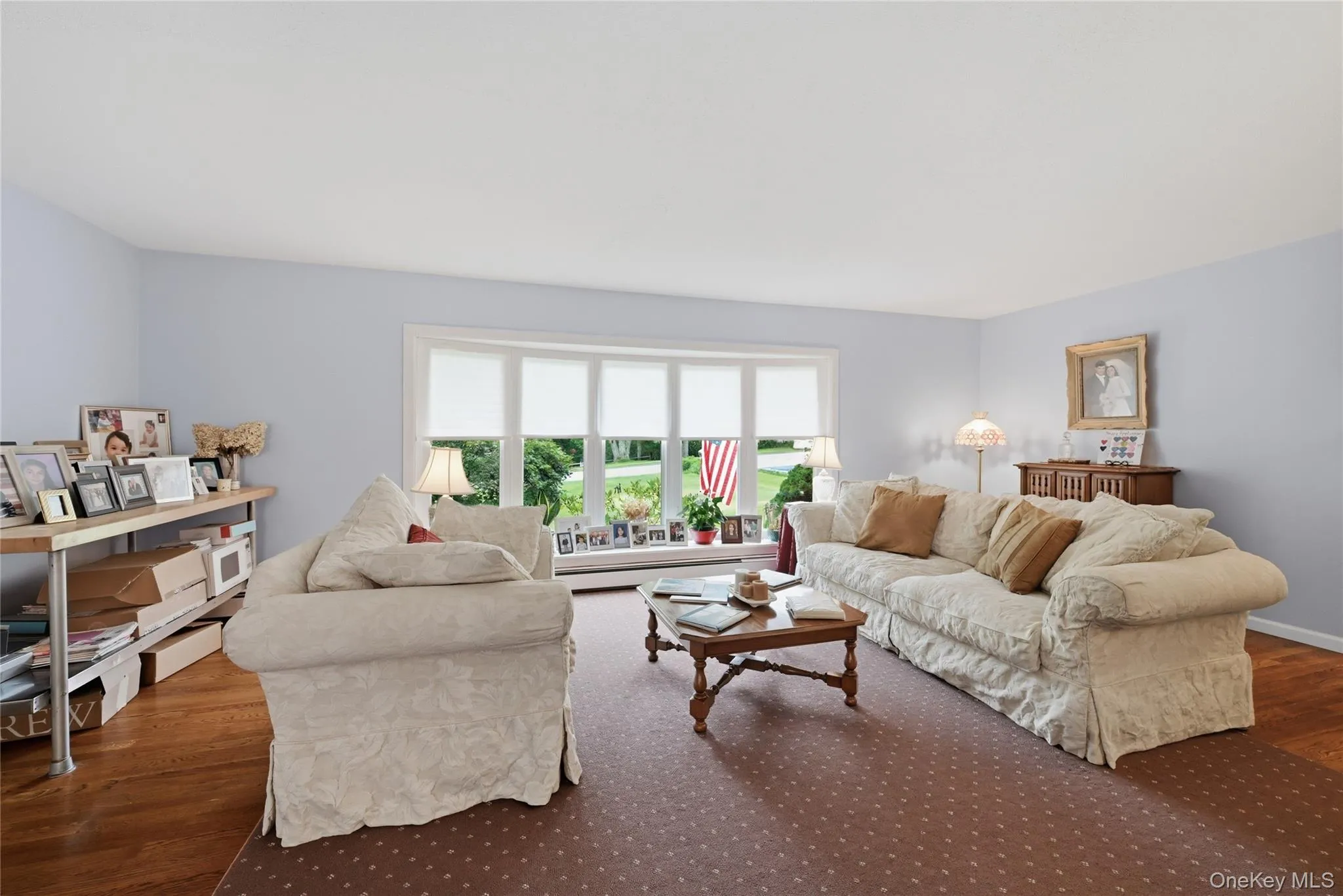 Second spacious living area featuring light-toned walls, a large bay window, and wood-finish flooring Second spacious living area featuring light-toned walls, a large bay window, and wood-finish flooring