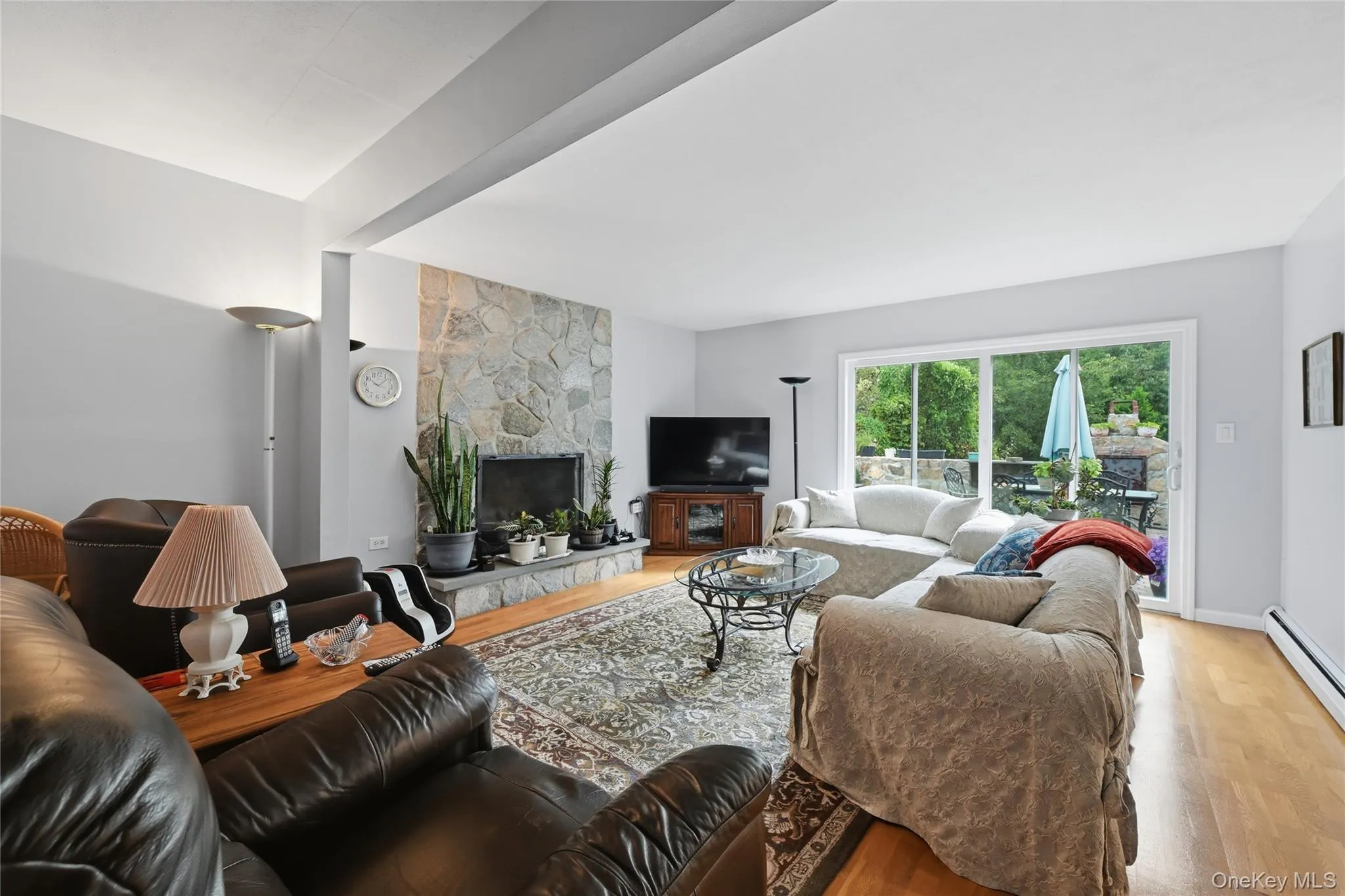 Stone fireplace with hearth, recessed lighting, wood-finish flooring, and sliding glass doors Stone fireplace with hearth, recessed lighting, wood-finish flooring, and sliding glass doors