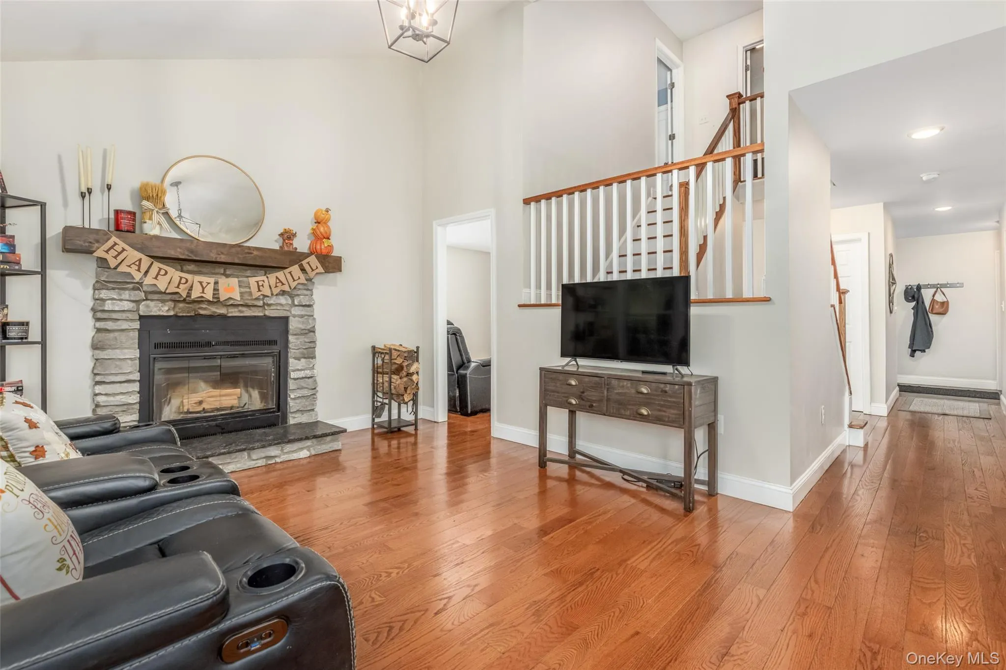 Vaulted ceiling, stone surround fireplace with wood mantel, wood-finish flooring, staircase with white spindles, and recessed lighting Vaulted ceiling, stone surround fireplace with wood mantel, wood-finish flooring, staircase with white spindles, and recessed lighting