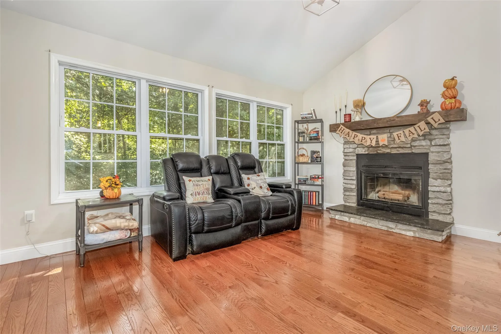 Hardwood flooring, vaulted ceiling, stone-clad fireplace with mantel, and large multi-pane windows Hardwood flooring, vaulted ceiling, stone-clad fireplace with mantel, and large multi-pane windows