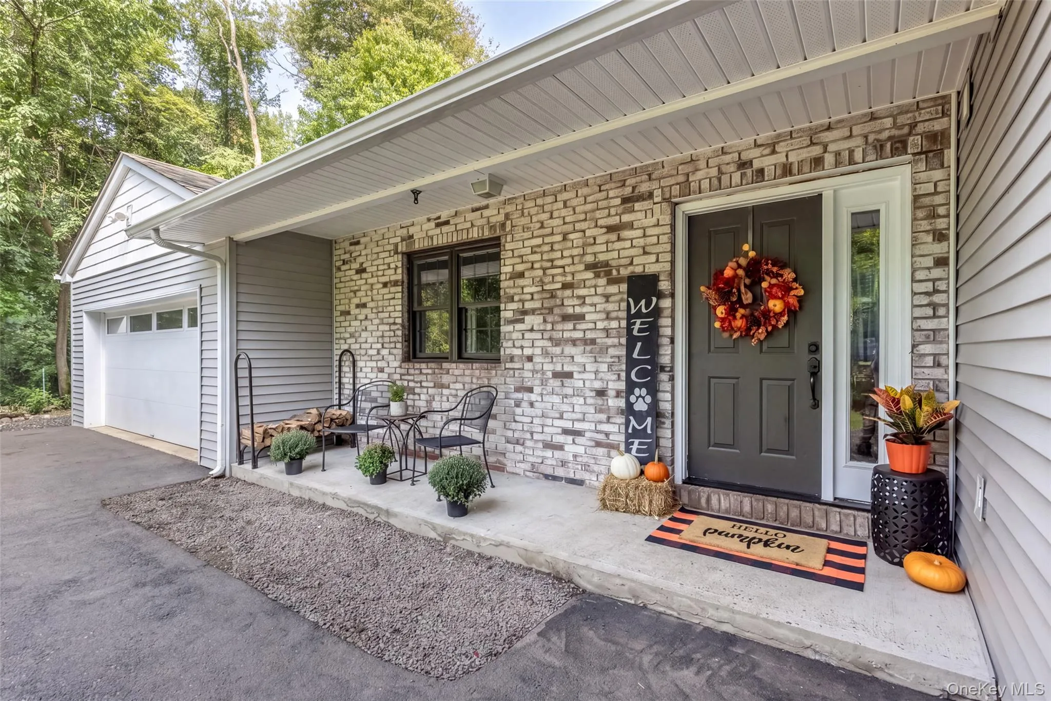 Front entry with brick and siding facade, featuring a covered porch, an entry door with a sidelight, and an attached garage with a white door Front entry with brick and siding facade, featuring a covered porch, an entry door with a sidelight, and an attached garage with a white door