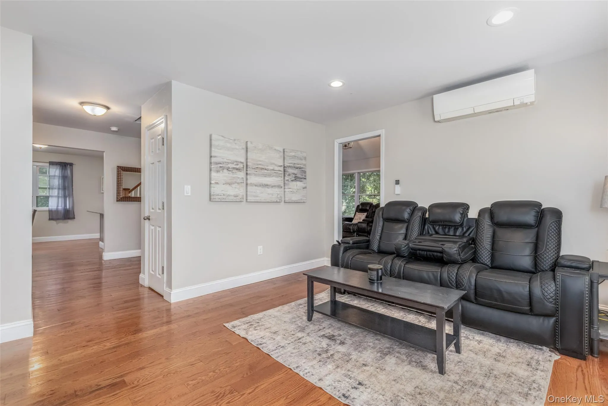 Hardwood flooring, recessed lighting, white trim, light wall paint, and a built-in split air conditioning unit Hardwood flooring, recessed lighting, white trim, light wall paint, and a built-in split air conditioning unit