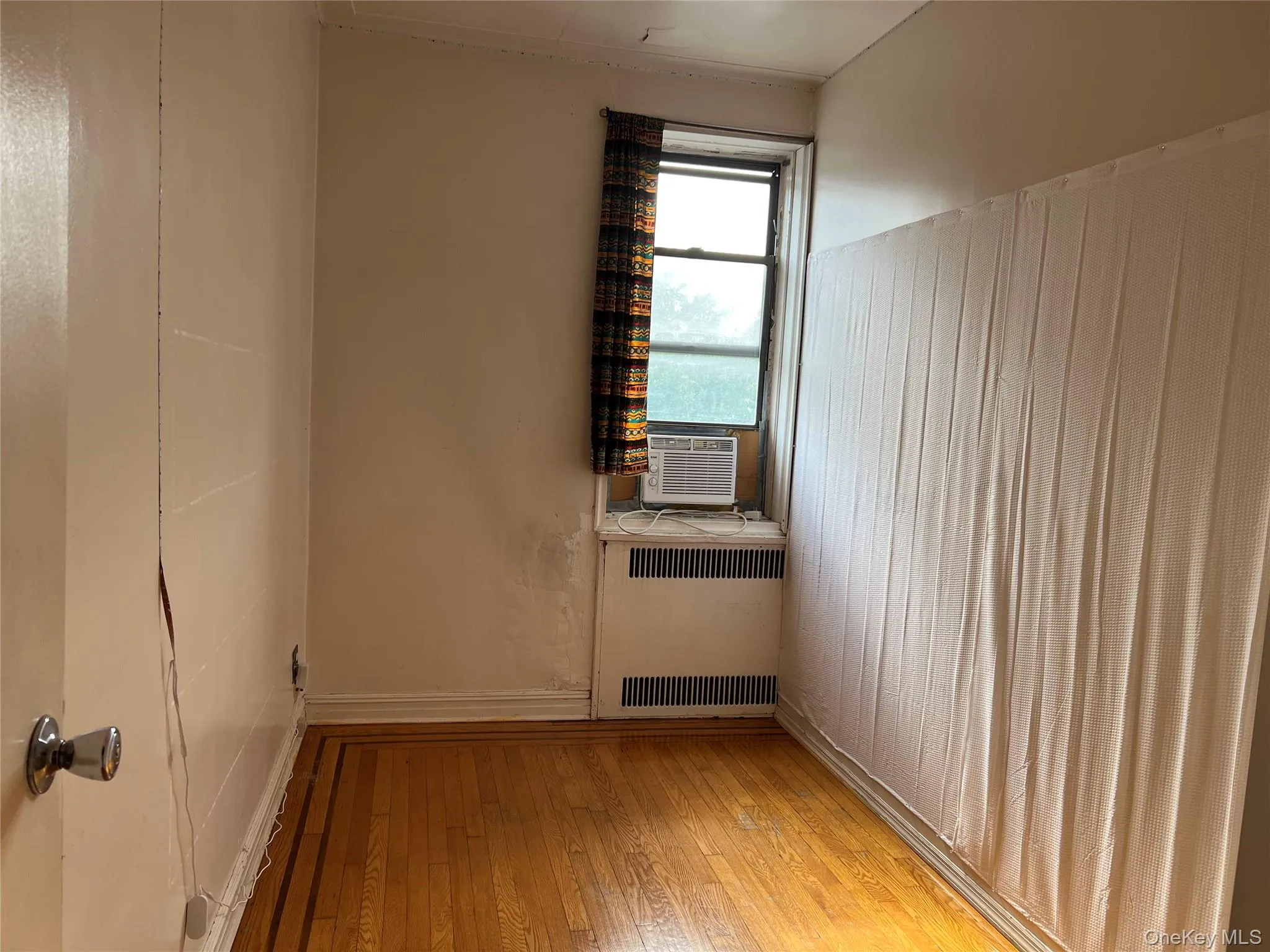 Unfurnished room with light wood-style flooring, radiator heating unit, cooling unit, and a water view Unfurnished room with light wood-style flooring, radiator heating unit, cooling unit, and a water view