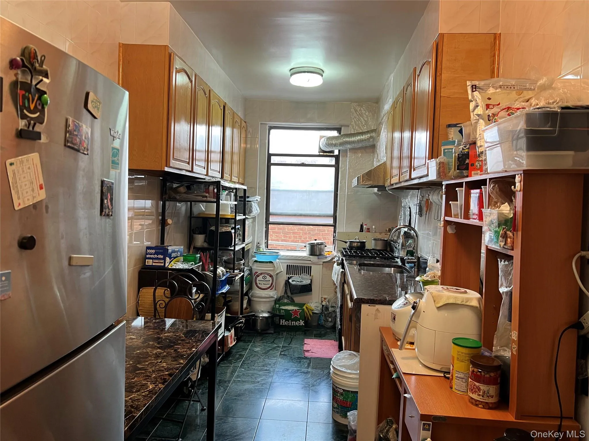 Kitchen featuring freestanding refrigerator and brown cabinetry Kitchen featuring freestanding refrigerator and brown cabinetry