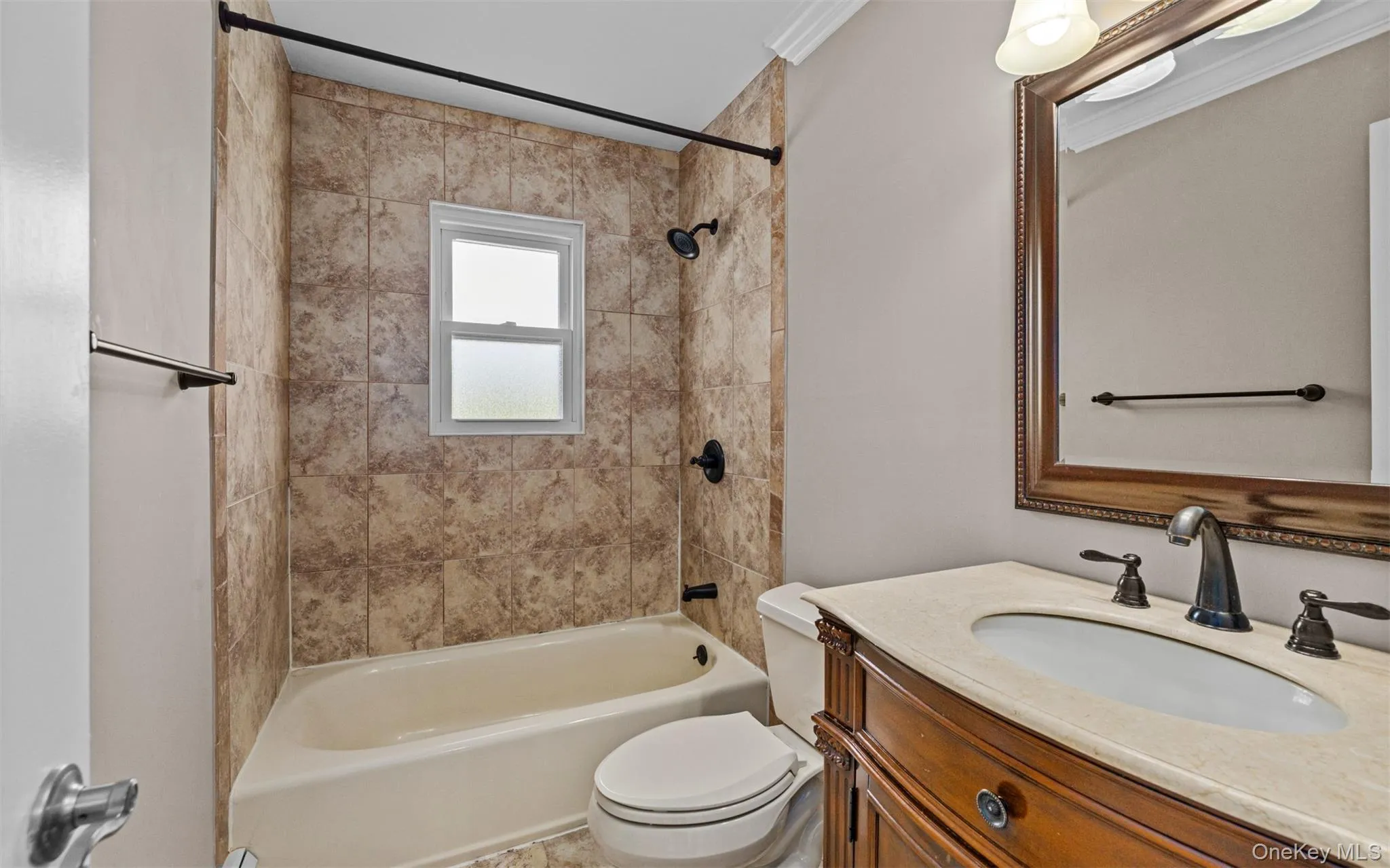 Bathroom featuring a bathtub with tile surround, shower, a built-in vanity with a stone countertop, a framed mirror, and crown molding Bathroom featuring a bathtub with tile surround, shower, a built-in vanity with a stone countertop, a framed mirror, and crown molding