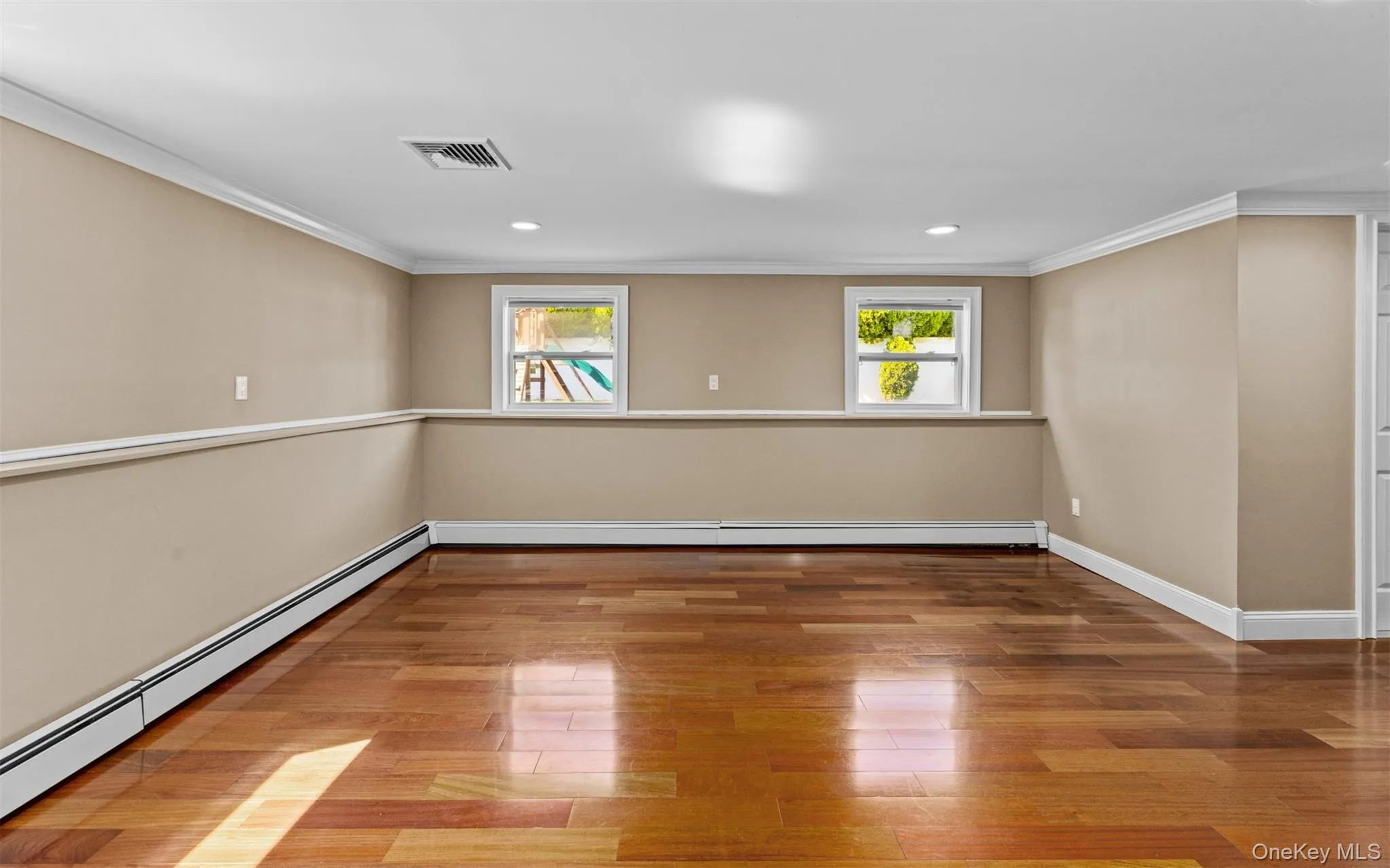 Cherry wood finish flooring, three windows with white trim, recessed lighting, crown molding, and chair rail detailing Cherry wood finish flooring, three windows with white trim, recessed lighting, crown molding, and chair rail detailing