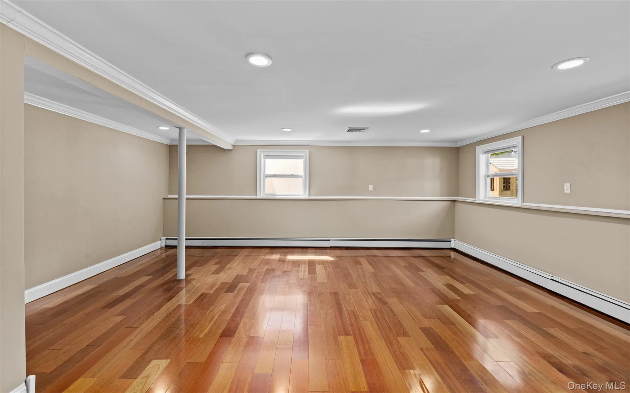 Cherry wood finish flooring, three windows with white trim, recessed lighting, crown molding, and chair rail detailing Cherry wood finish flooring, three windows with white trim, recessed lighting, crown molding, and chair rail detailing