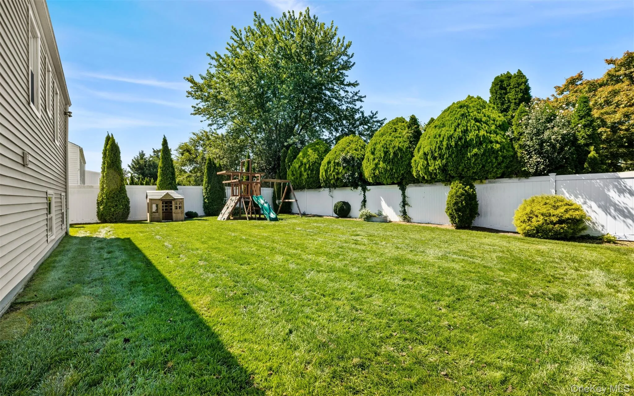 Expansive lawn area, white privacy fencing, and mature perimeter landscaping, fully fenced and In-ground speakers Expansive lawn area, white privacy fencing, and mature perimeter landscaping, fully fenced and In-ground speakers
