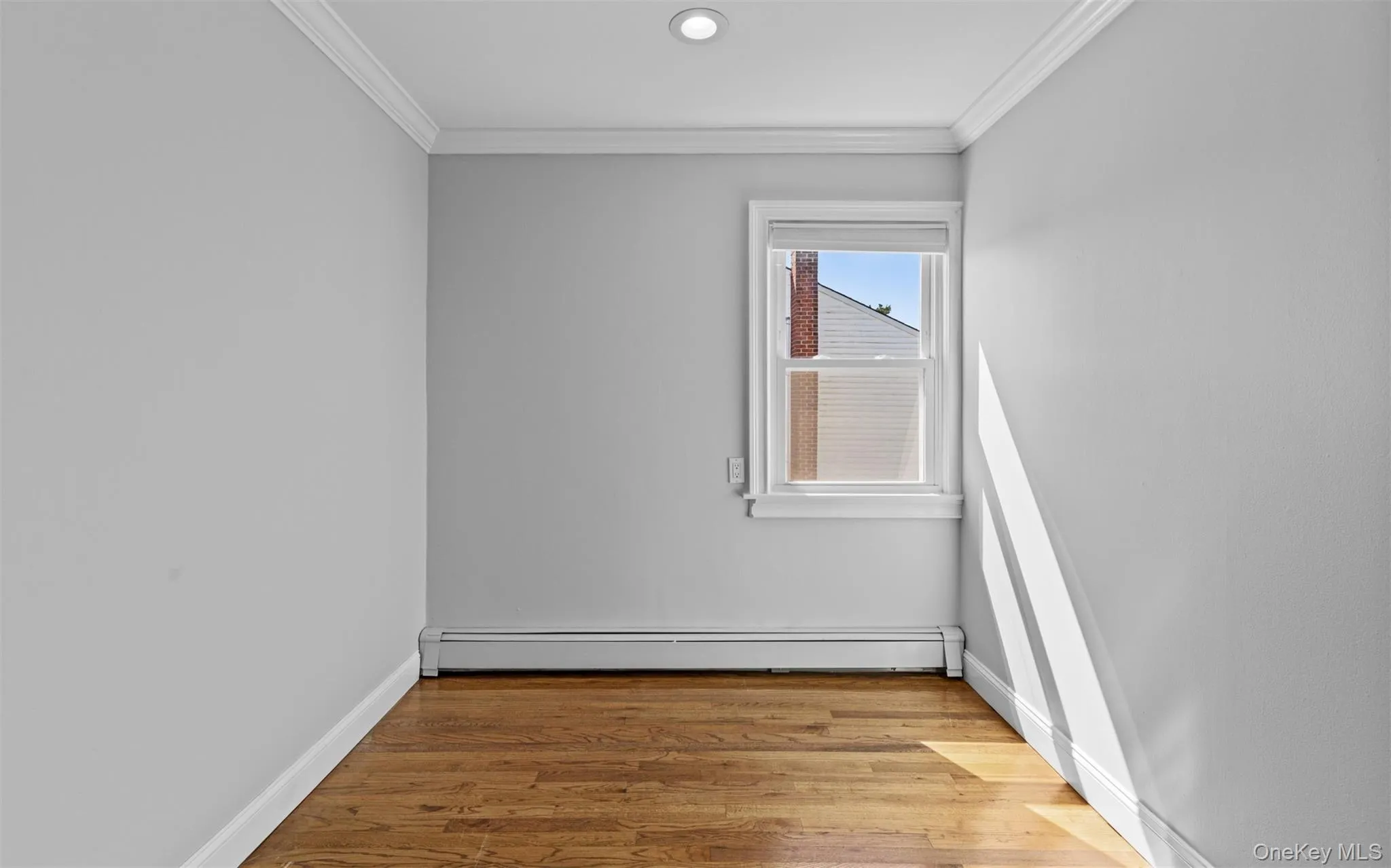 Recessed ceiling lighting, crown molding, wood-finish flooring, single window, and a wall-mounted radiator Recessed ceiling lighting, crown molding, wood-finish flooring, single window, and a wall-mounted radiator