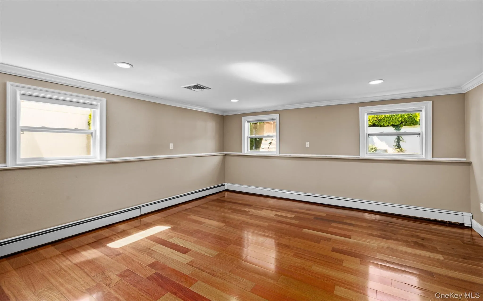 Cherry wood finish flooring, three windows with white trim, recessed lighting, crown molding, and chair rail detailing Cherry wood finish flooring, three windows with white trim, recessed lighting, crown molding, and chair rail detailing