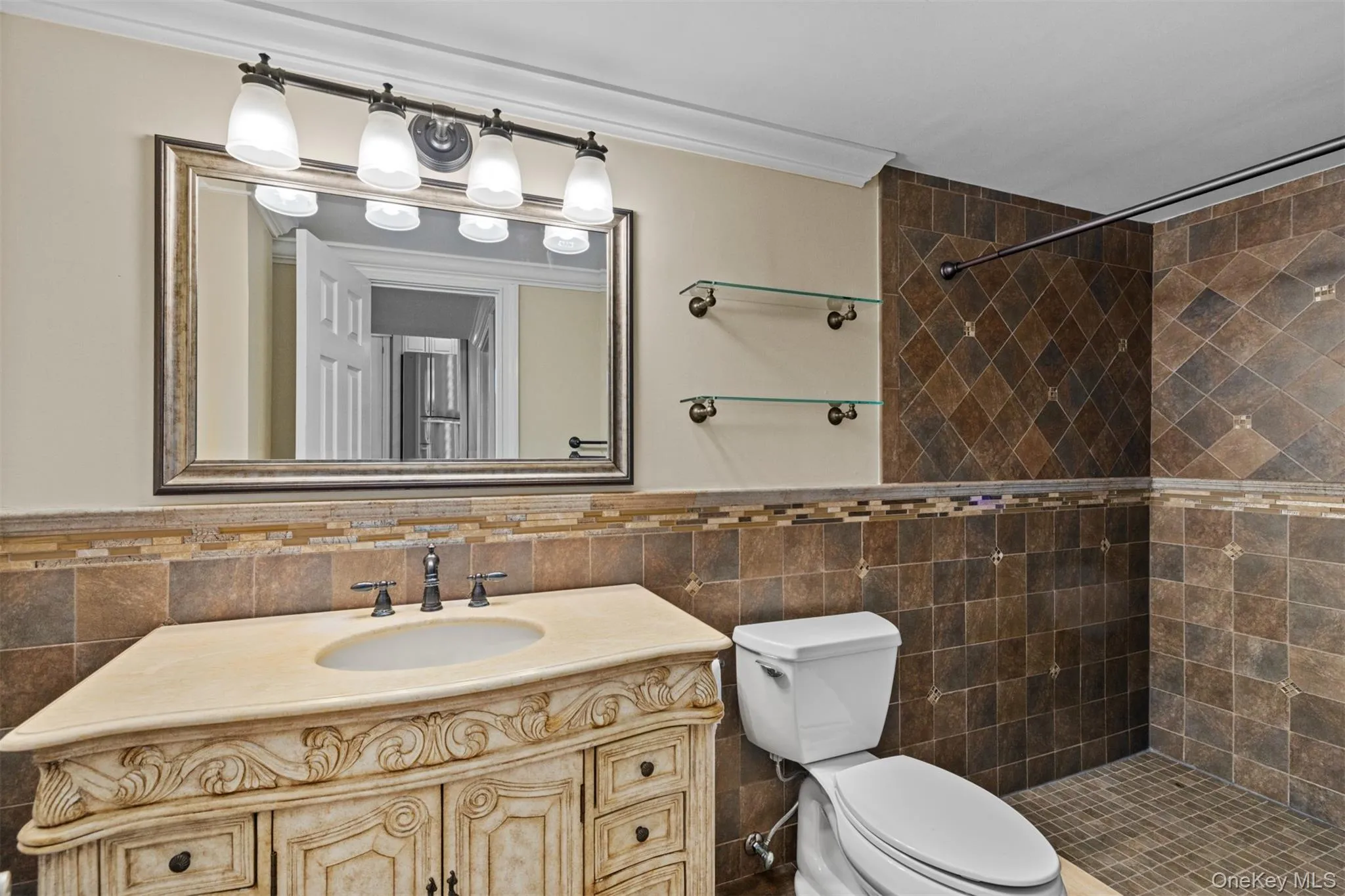 Ornate vanity with integrated sink, bronze-tone faucet, and custom tile backsplash, walk-in shower, crown molding Ornate vanity with integrated sink, bronze-tone faucet, and custom tile backsplash, walk-in shower, crown molding