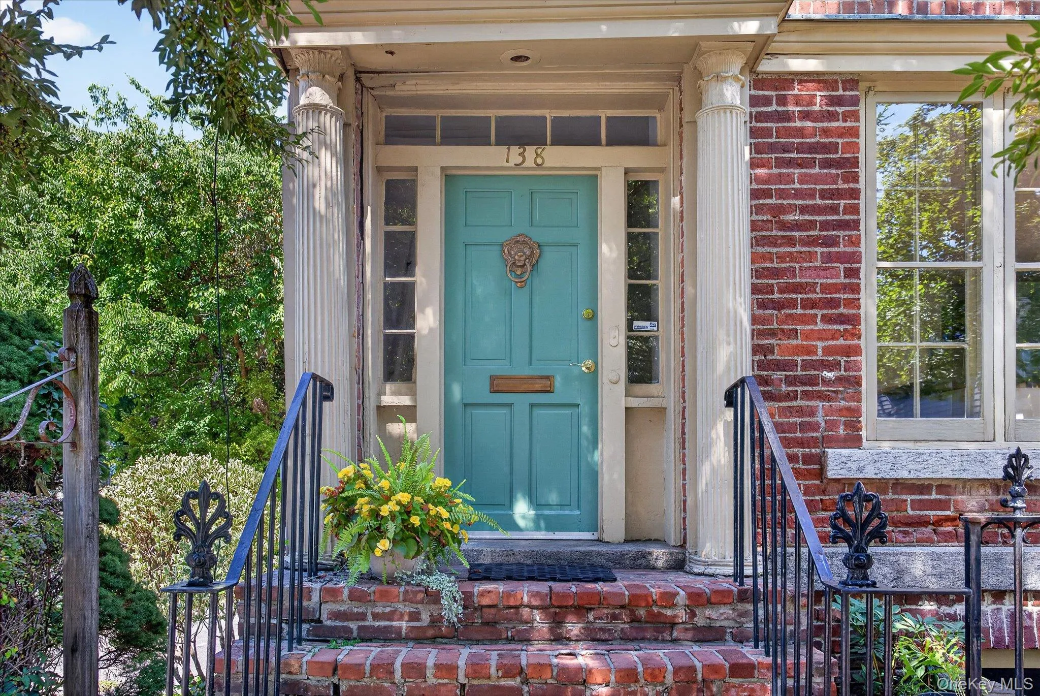 Brick exterior featuring a teal paneled door, fluted columns, sidelight windows, and transom window Brick exterior featuring a teal paneled door, fluted columns, sidelight windows, and transom window