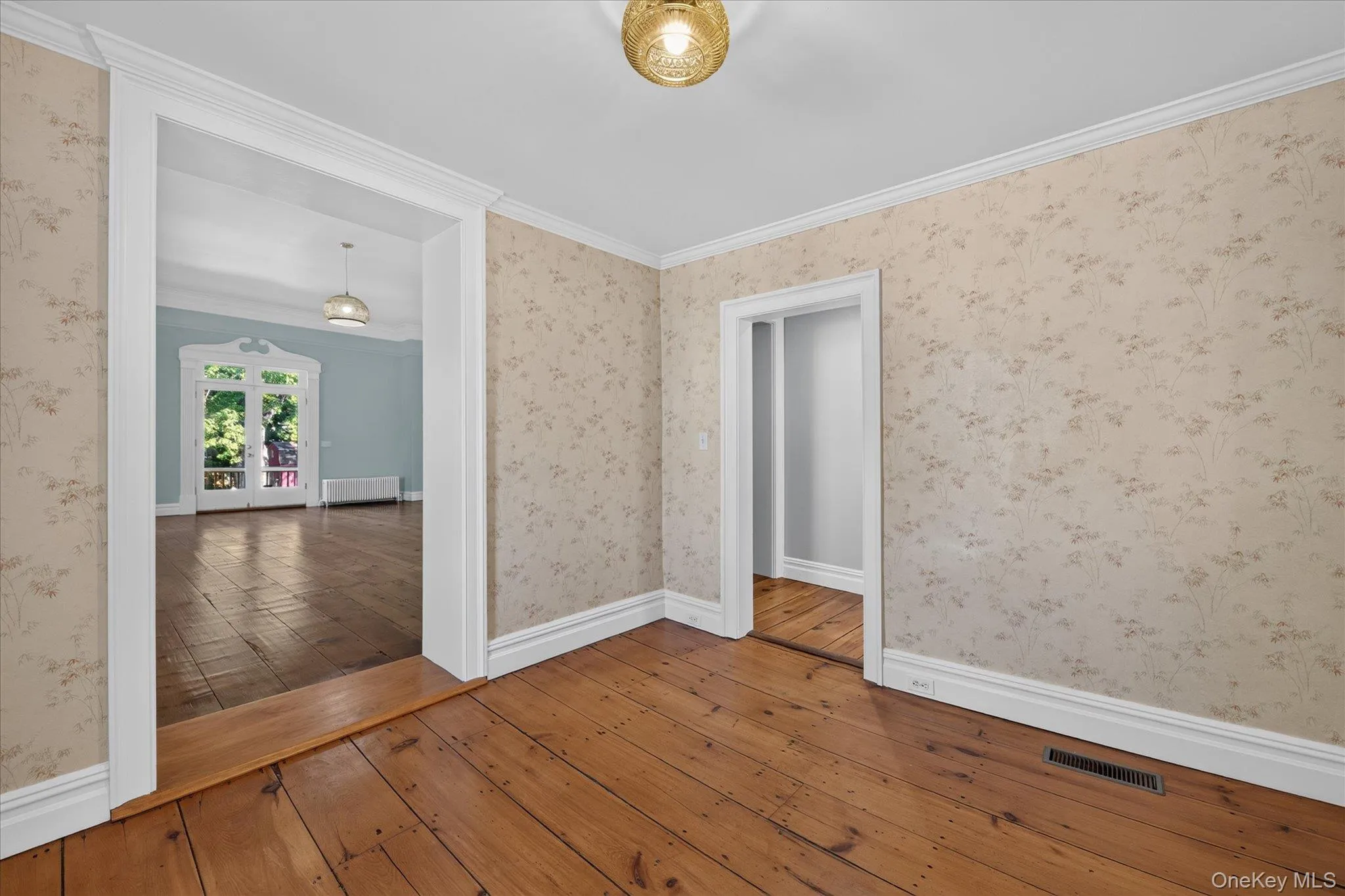 Hardwood flooring throughout, decorative wallpaper, crown molding, and ornate trim around doorways Hardwood flooring throughout, decorative wallpaper, crown molding, and ornate trim around doorways