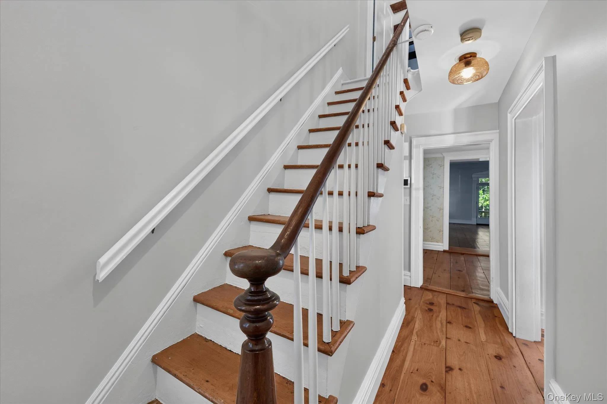 Hardwood flooring, painted stairs with wood treads, white balusters, dark wood handrail, and white trim Hardwood flooring, painted stairs with wood treads, white balusters, dark wood handrail, and white trim