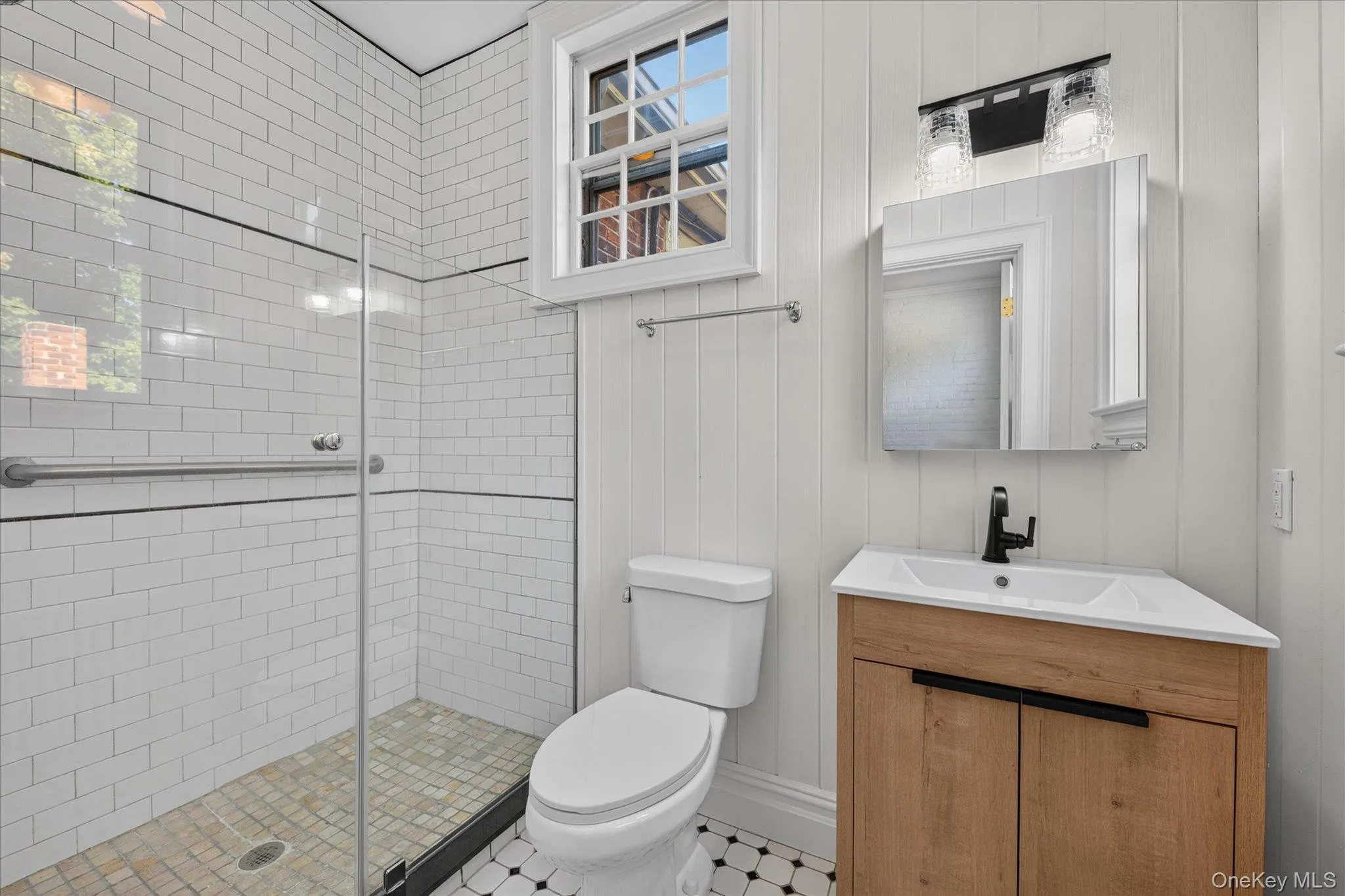 Walk-in shower with subway tile surround, clear glass enclosure, and mosaic tile flooring Walk-in shower with subway tile surround, clear glass enclosure, and mosaic tile flooring