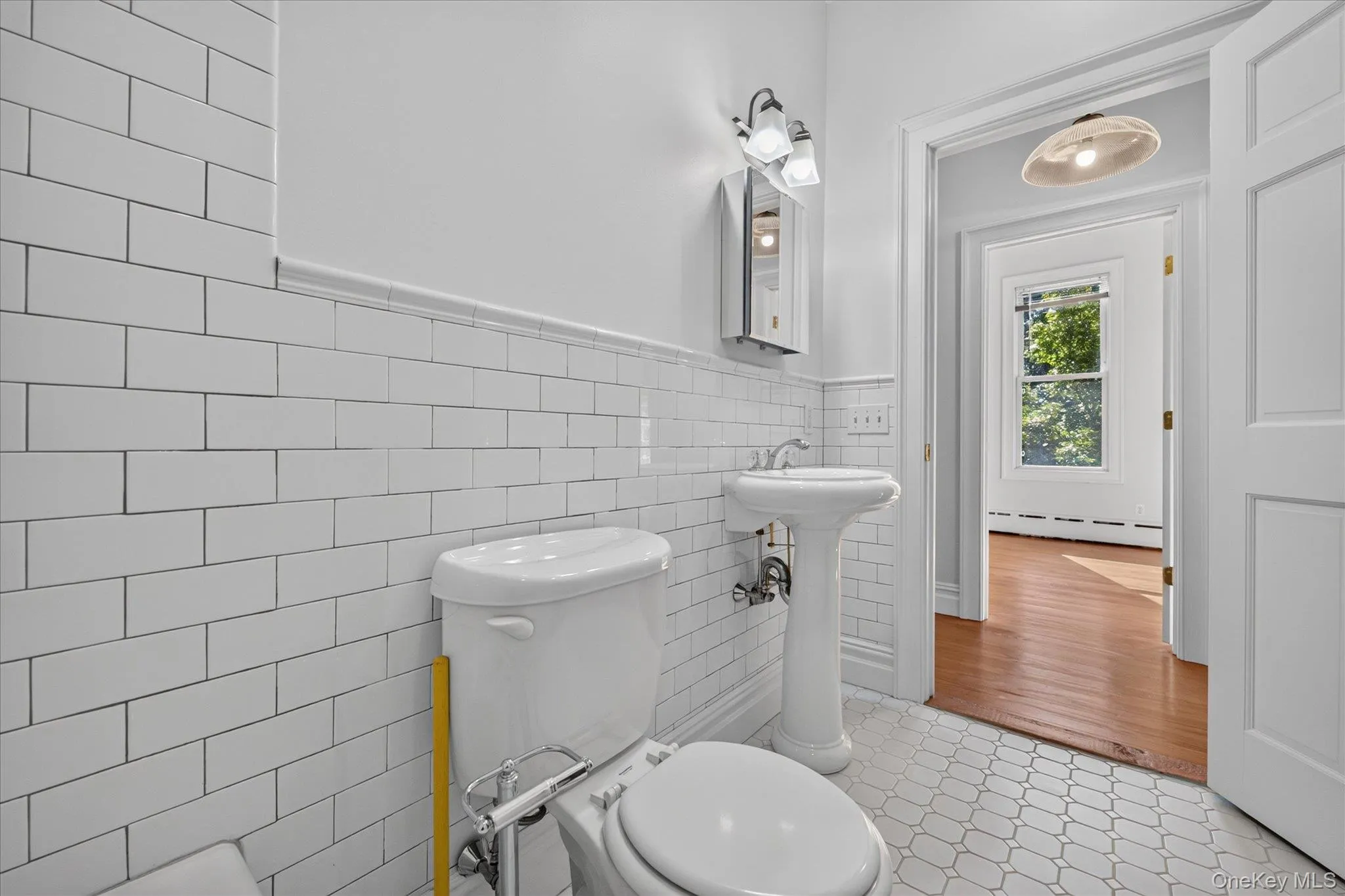 2nd full bathroom featuring a pedestal sink, subway tile wainscoting, and mosaic tile flooring 2nd full bathroom featuring a pedestal sink, subway tile wainscoting, and mosaic tile flooring