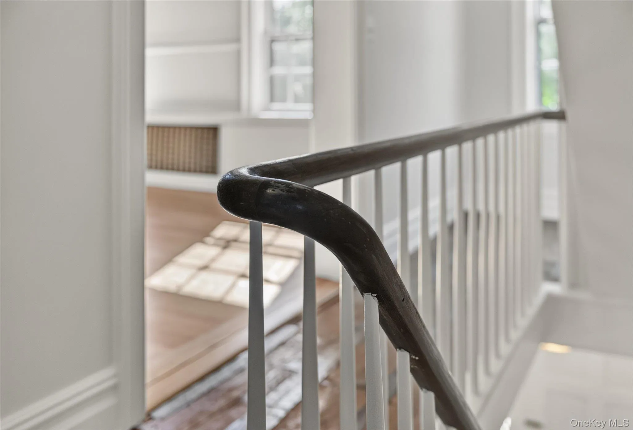 Hardwood flooring, painted white walls, white balusters, and a dark wood handrail Hardwood flooring, painted white walls, white balusters, and a dark wood handrail