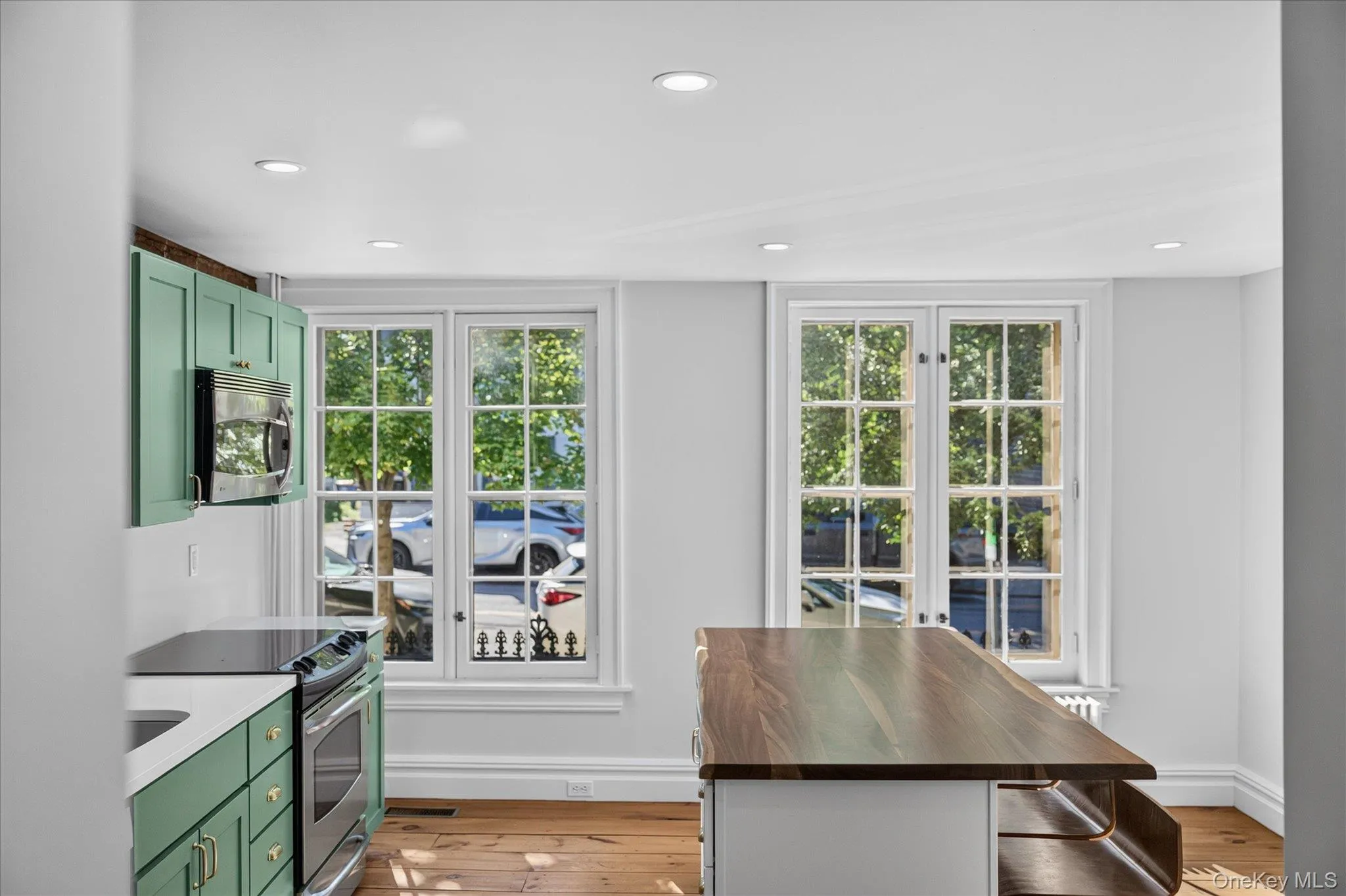 Kitchen featuring recessed lighting, a wood-finish island countertop, sage green cabinetry, stainless steel appliances, and wood-finish flooring Kitchen featuring recessed lighting, a wood-finish island countertop, sage green cabinetry, stainless steel appliances, and wood-finish flooring