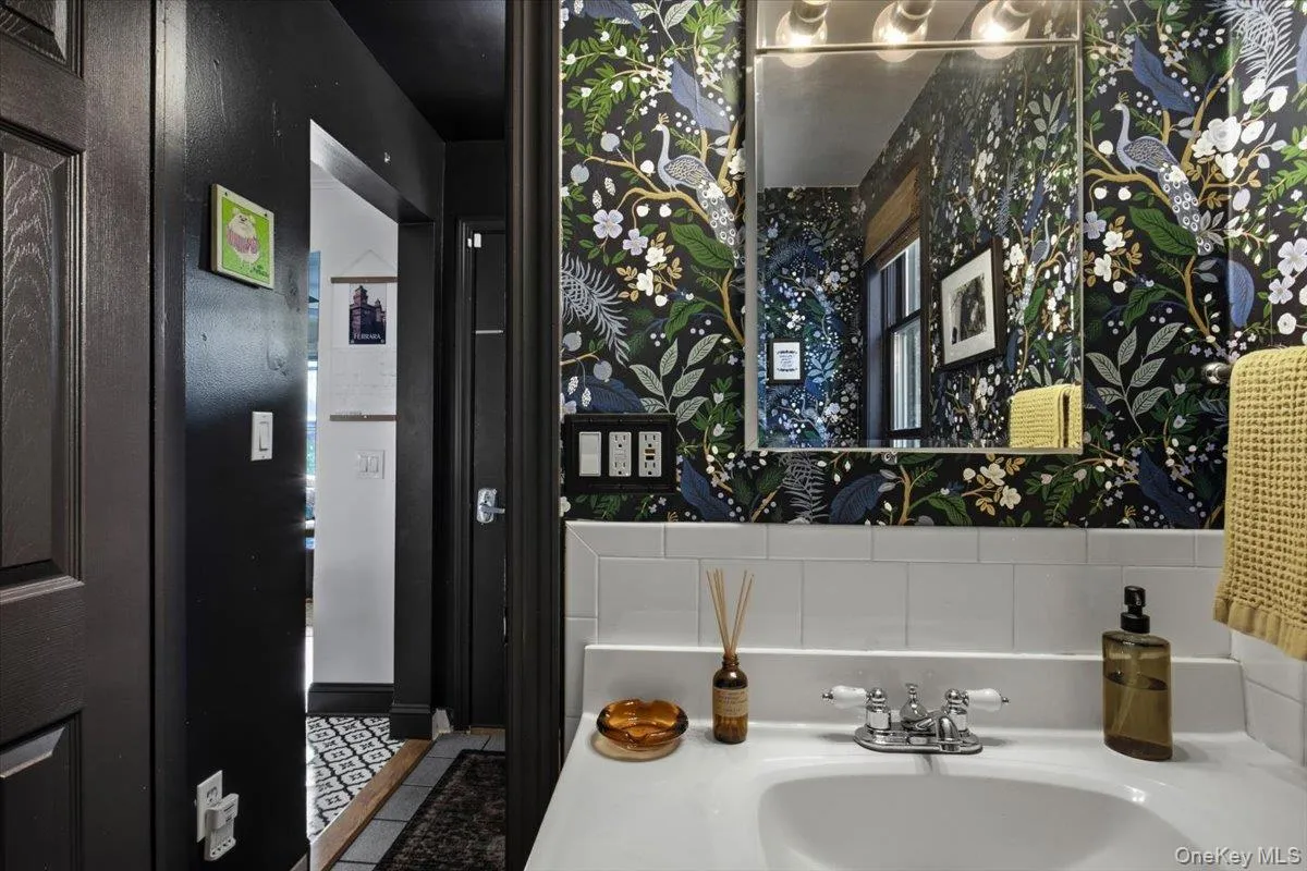View of the lower level full bathroom with a stand up shower, vanity and elegant wall covering. View of the lower level full bathroom with a stand up shower, vanity and elegant wall covering.