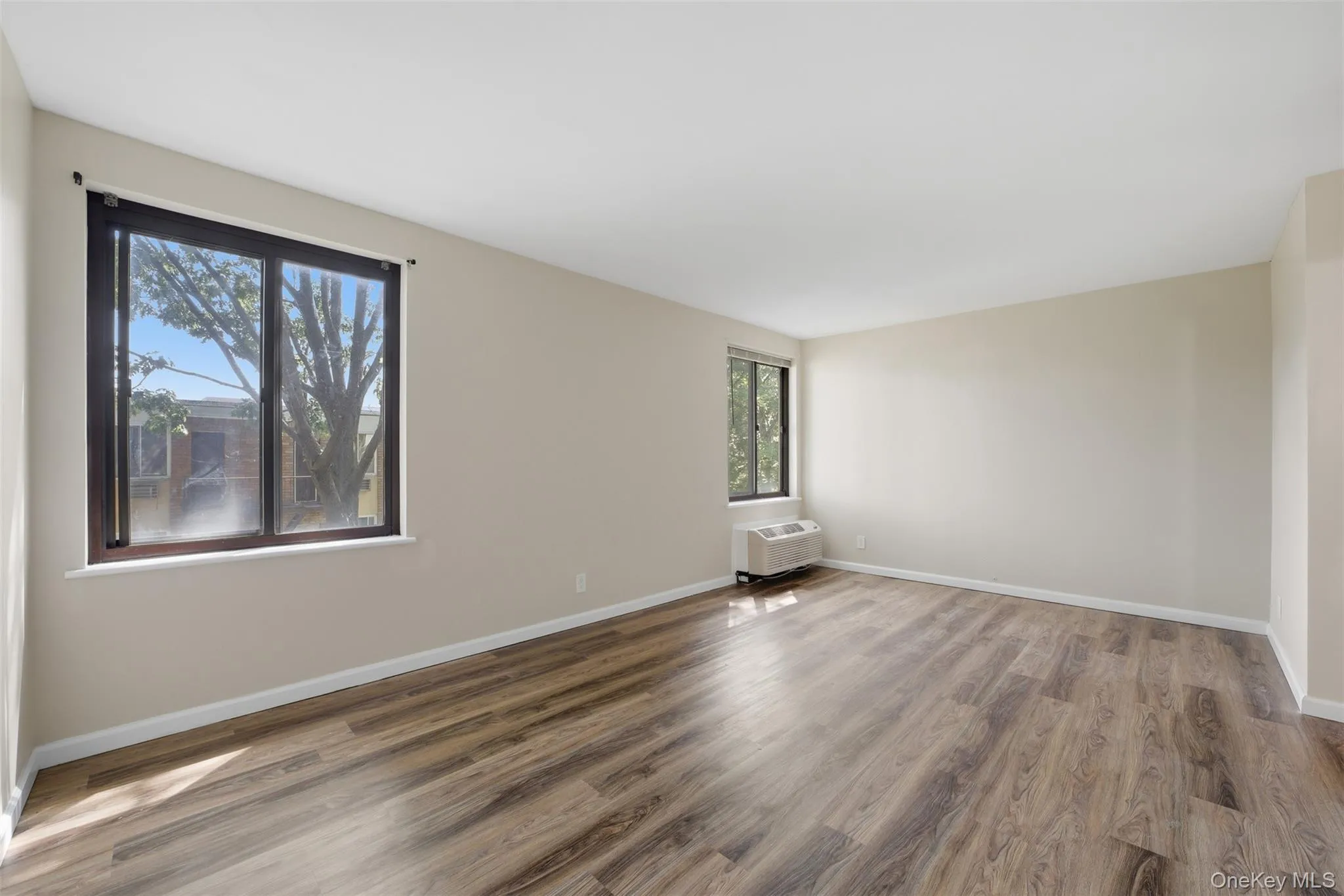 Large primary bedroom with new flooring and an abundance of sunlight Large primary bedroom with new flooring and an abundance of sunlight